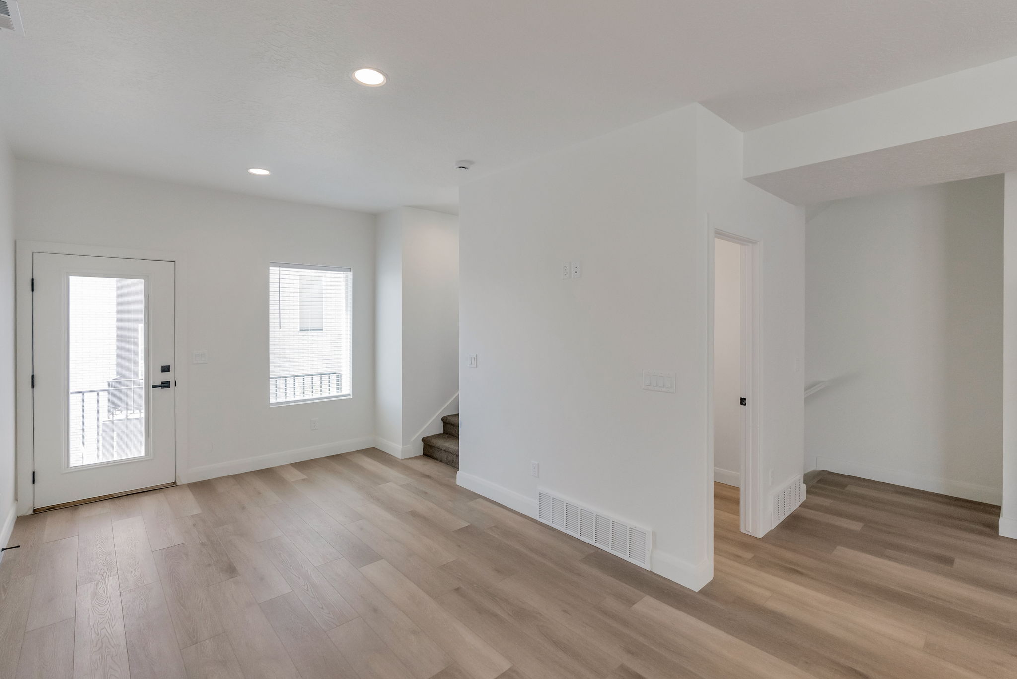 Open-concept living space with light wood-finish flooring, white walls, and recessed lighting
