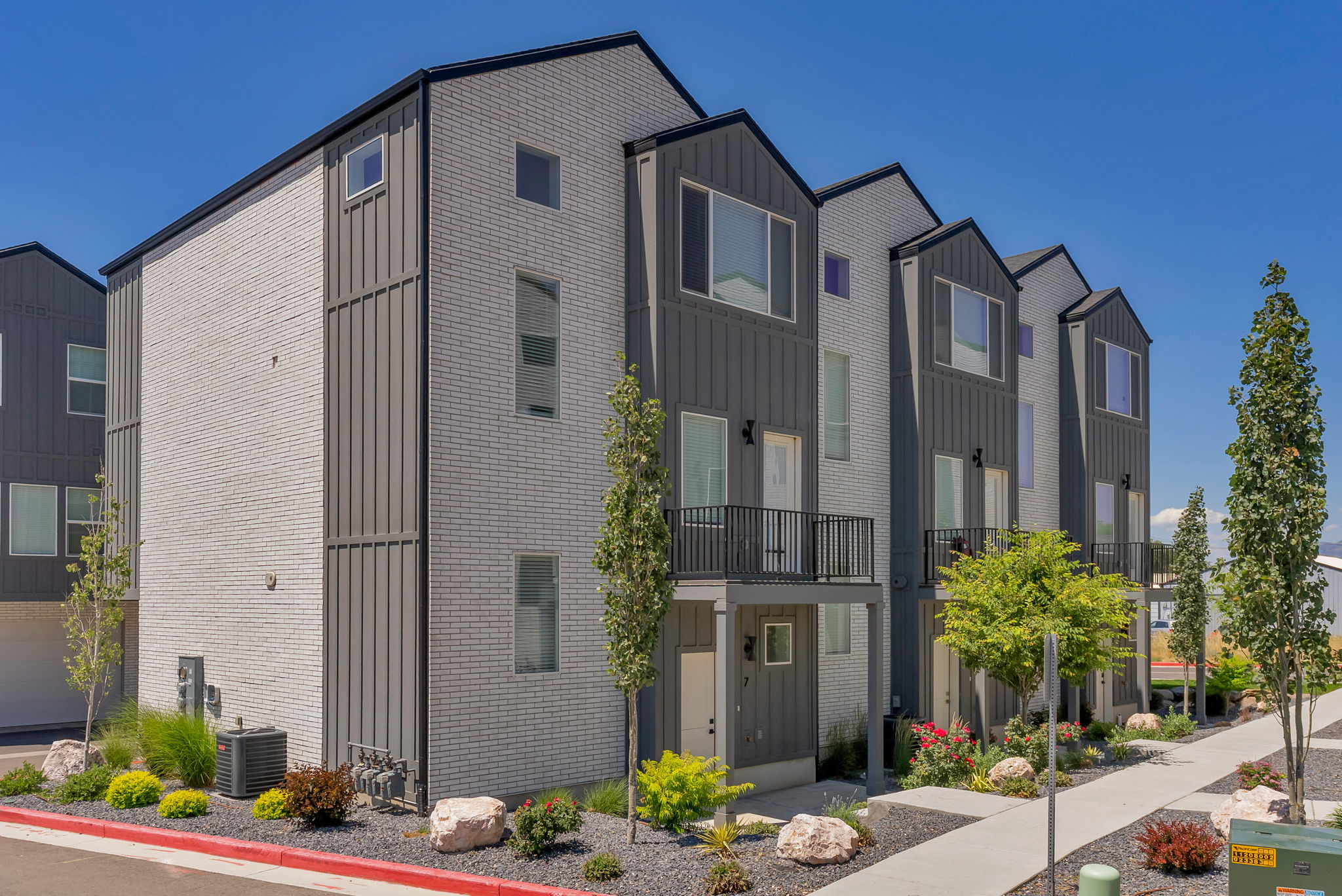 Contemporary townhome exterior featuring light gray brick and dark gray vertical siding
