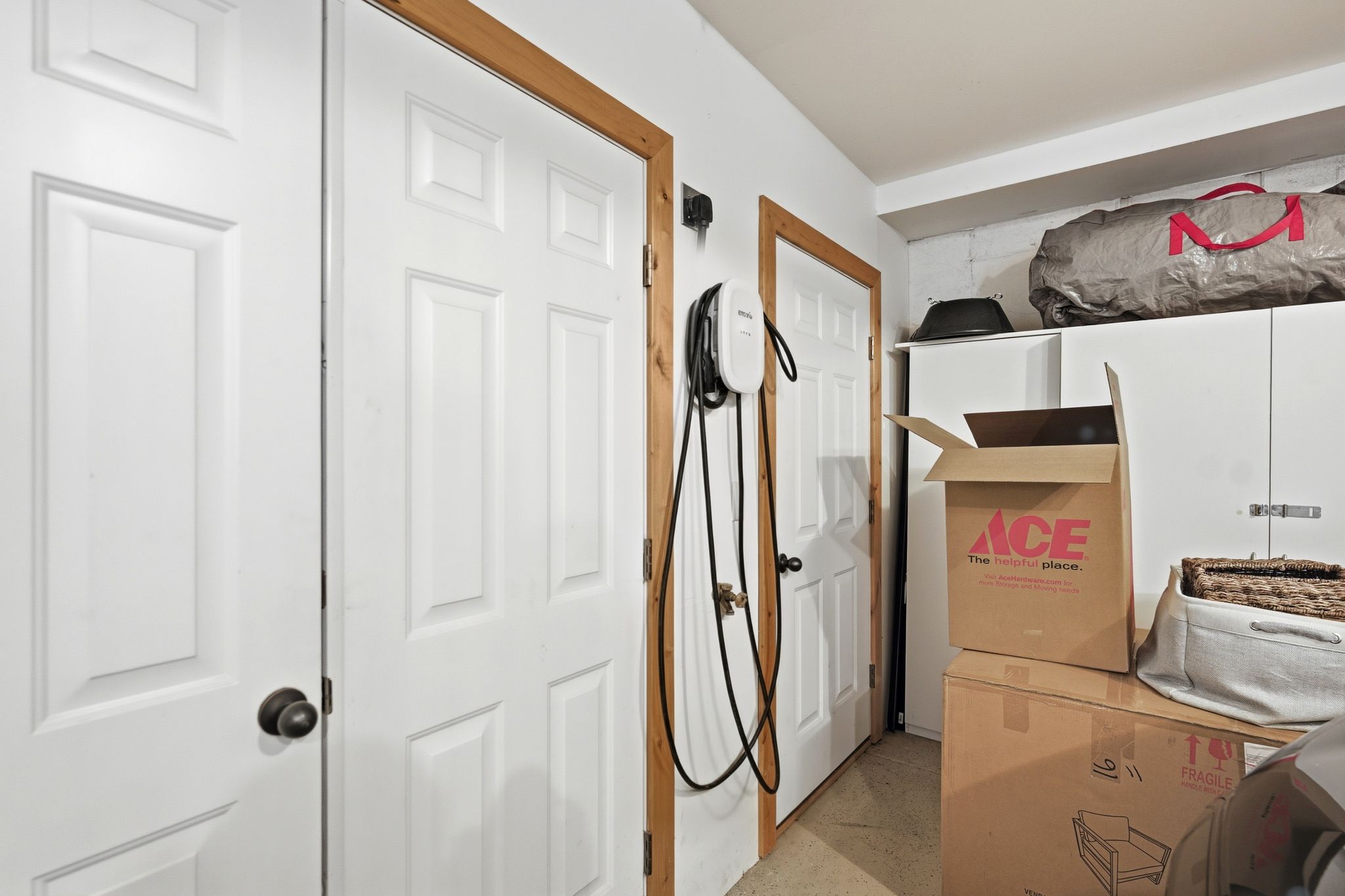 Utility area featuring multiple paneled doors with contrasting wood trim, an installed EV charging station, and built-in white cabinetry