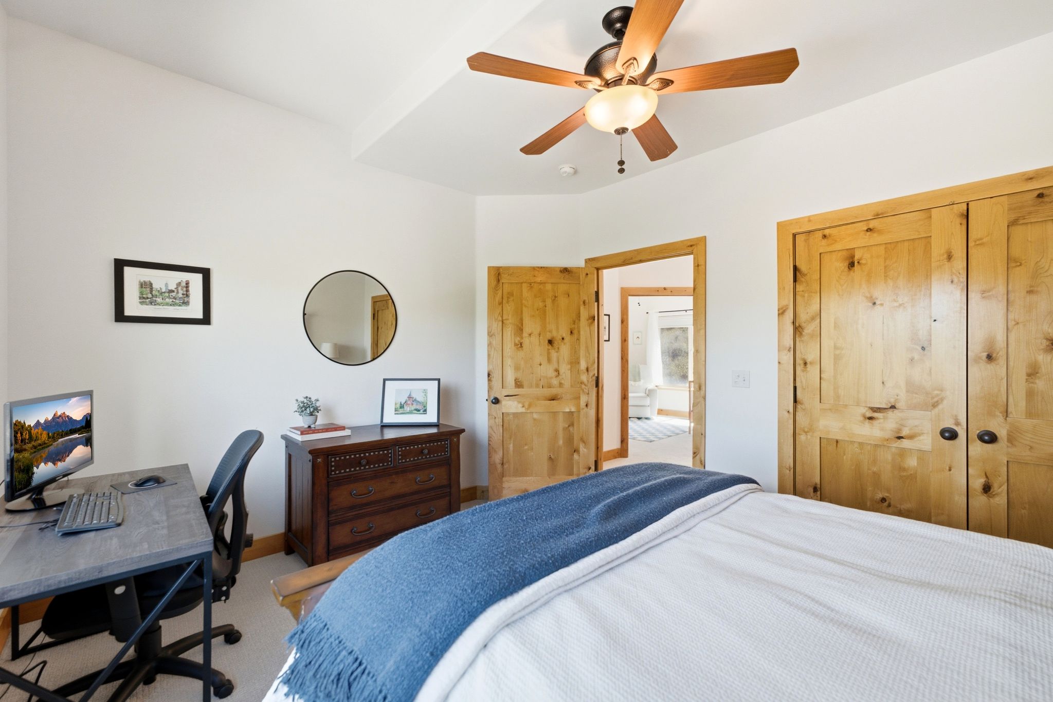 Bedroom featuring natural wood doors and trim, a tray ceiling, and a ceiling fan with integrated lighting