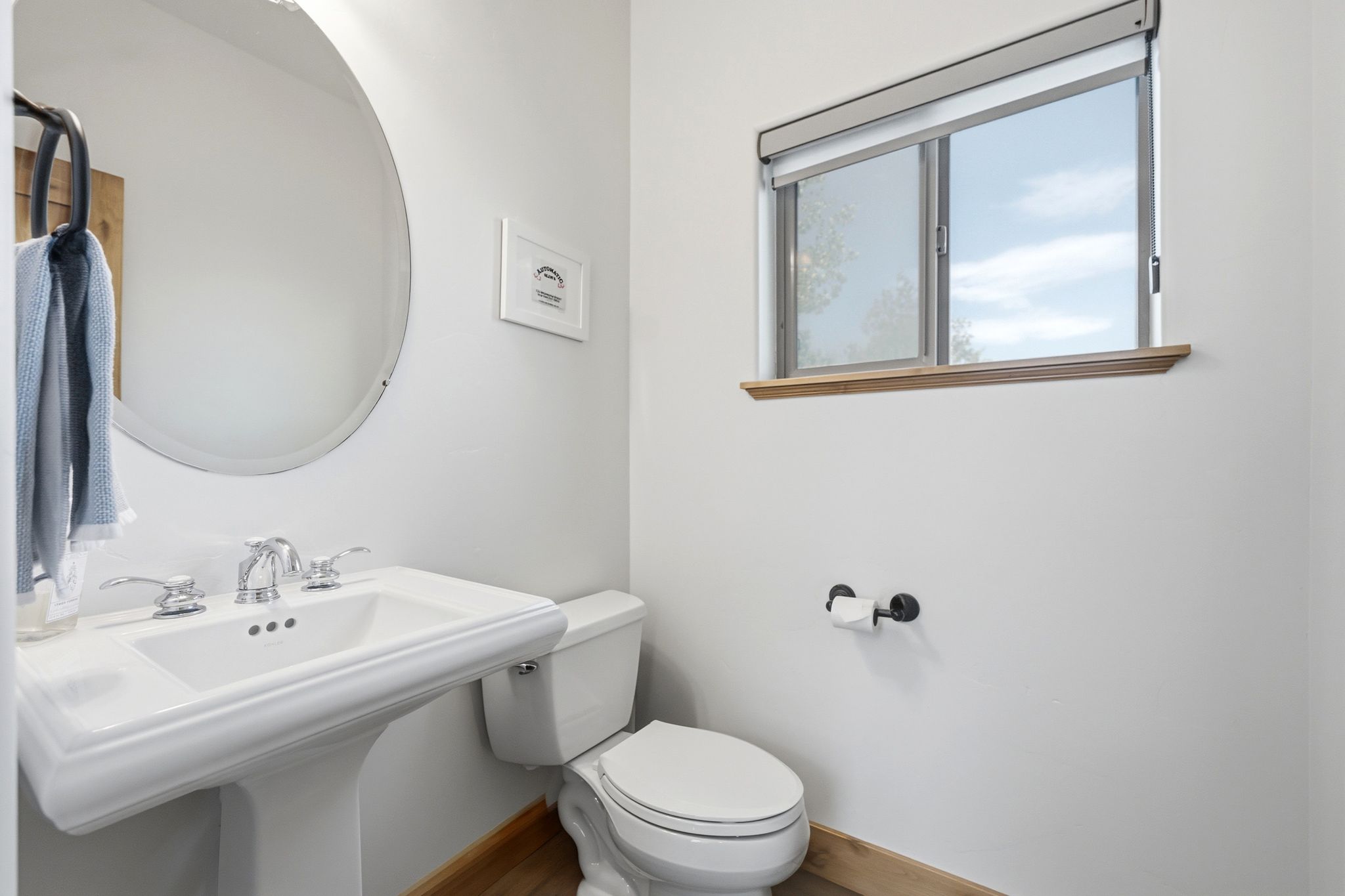 Pedestal sink with chrome fixtures and a circular mirror