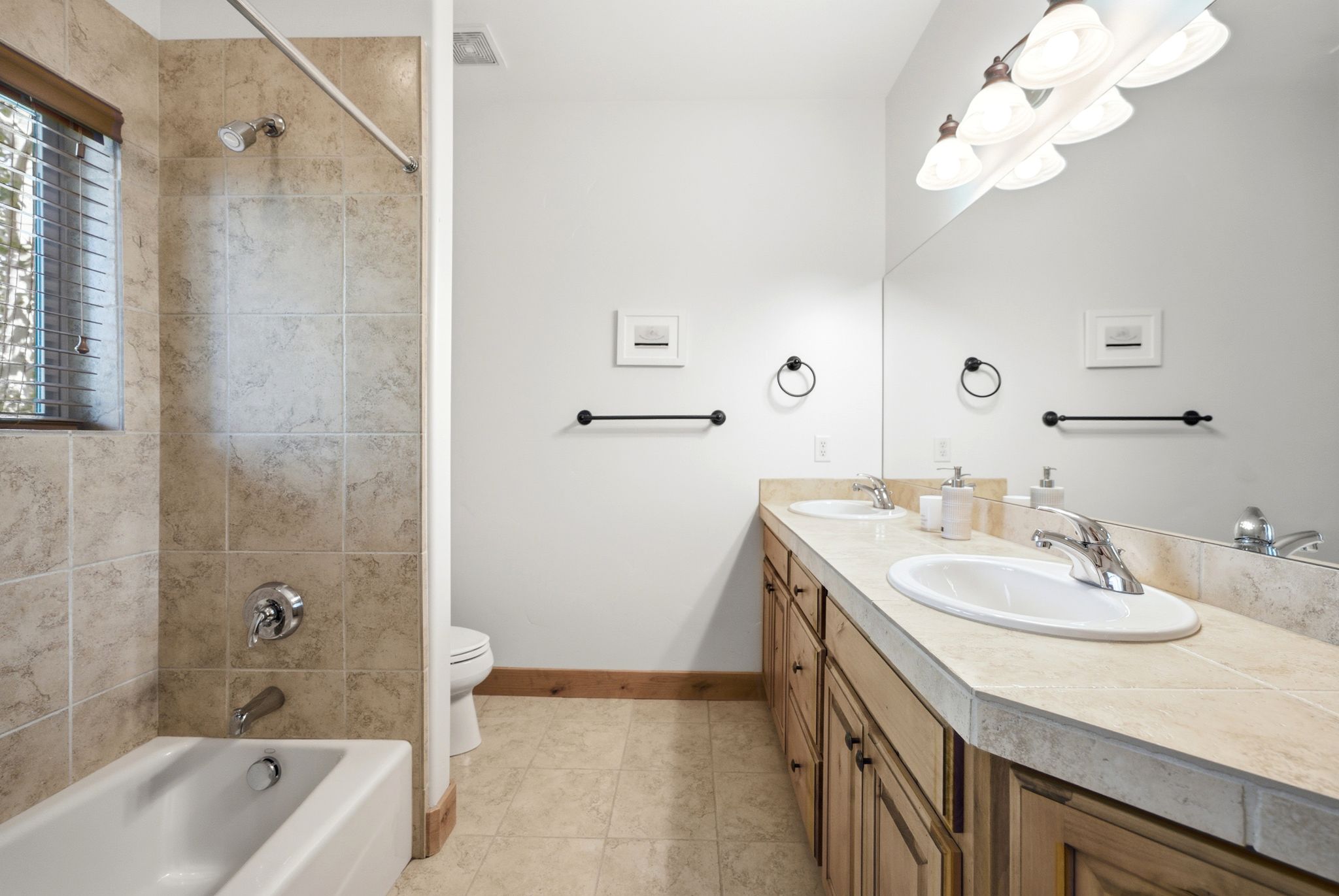 Bathroom featuring a double vanity with integrated sinks, a full-width mirror, and a five-light fixture