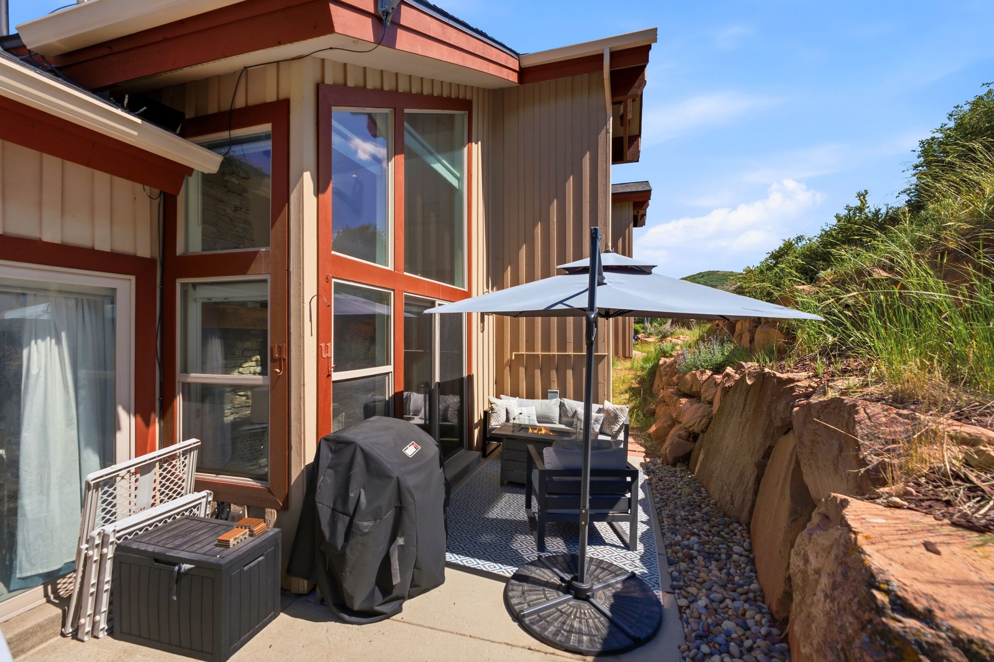 Expansive concrete patio area with a stone retaining wall and natural rock landscaping