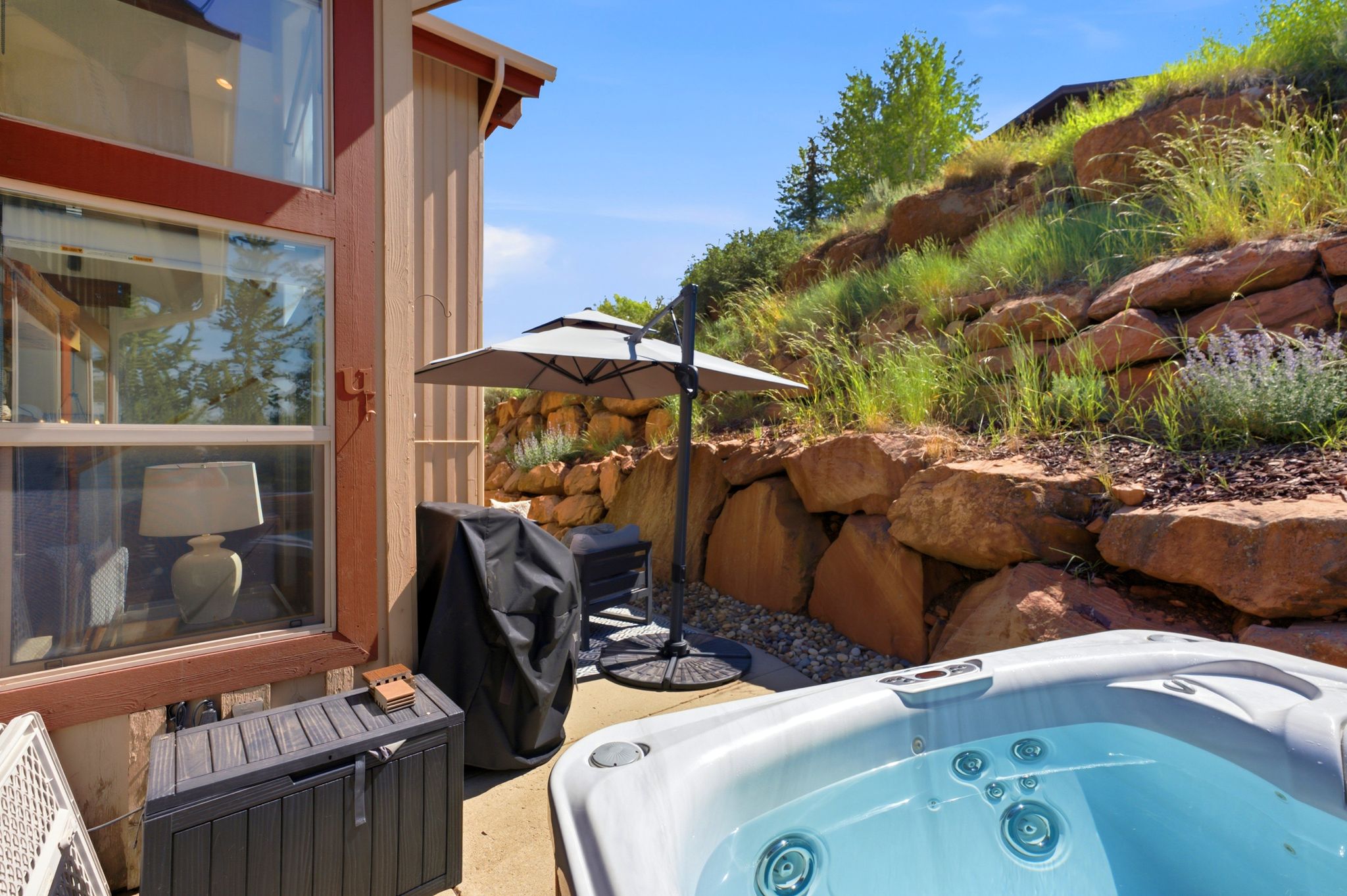 Outdoor patio featuring an inground hot tub, concrete paving, and a retaining wall constructed from large natural stone blocks