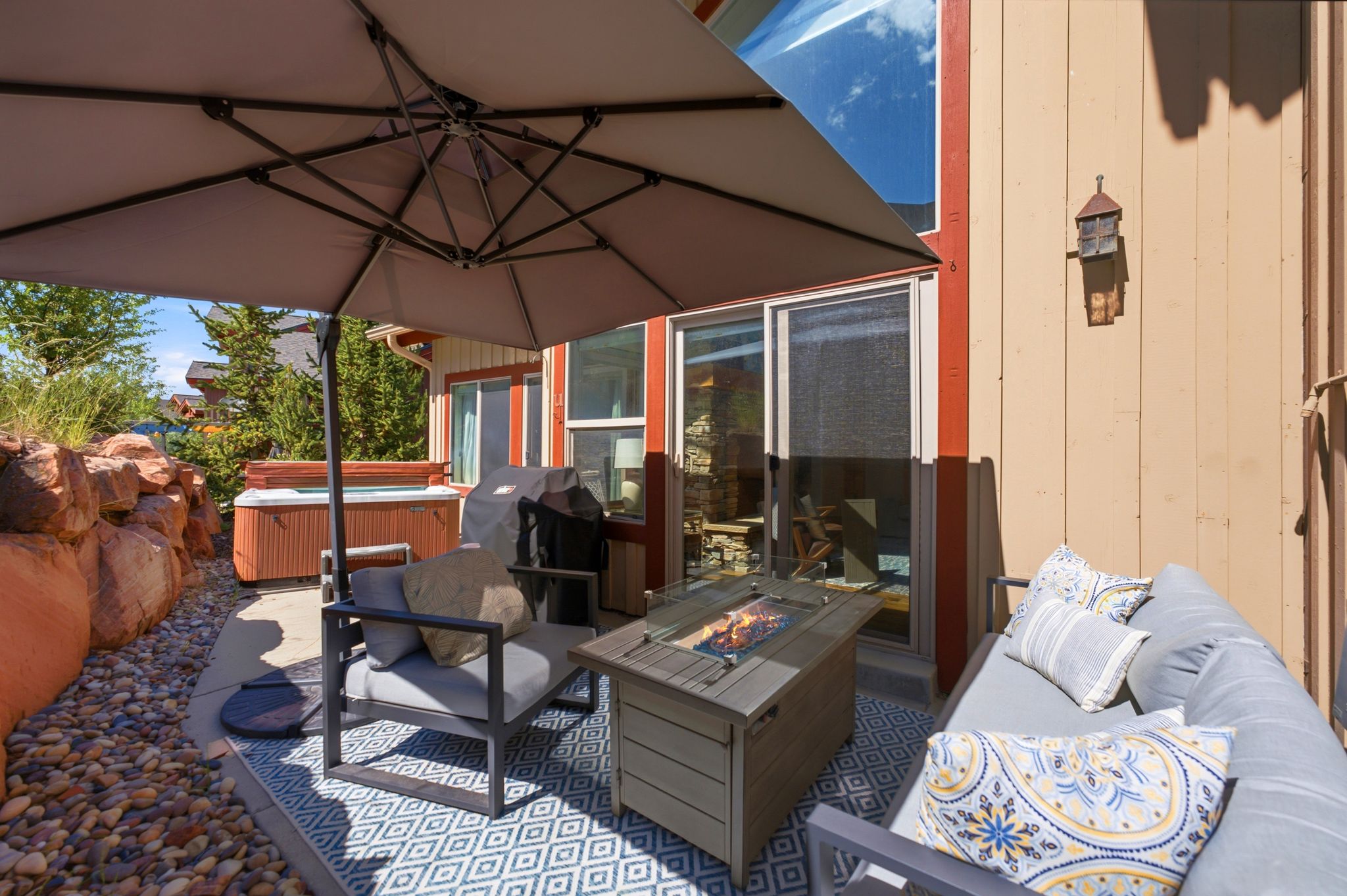 Outdoor patio featuring a built-in fire pit, sliding glass door, and exterior wall sconce