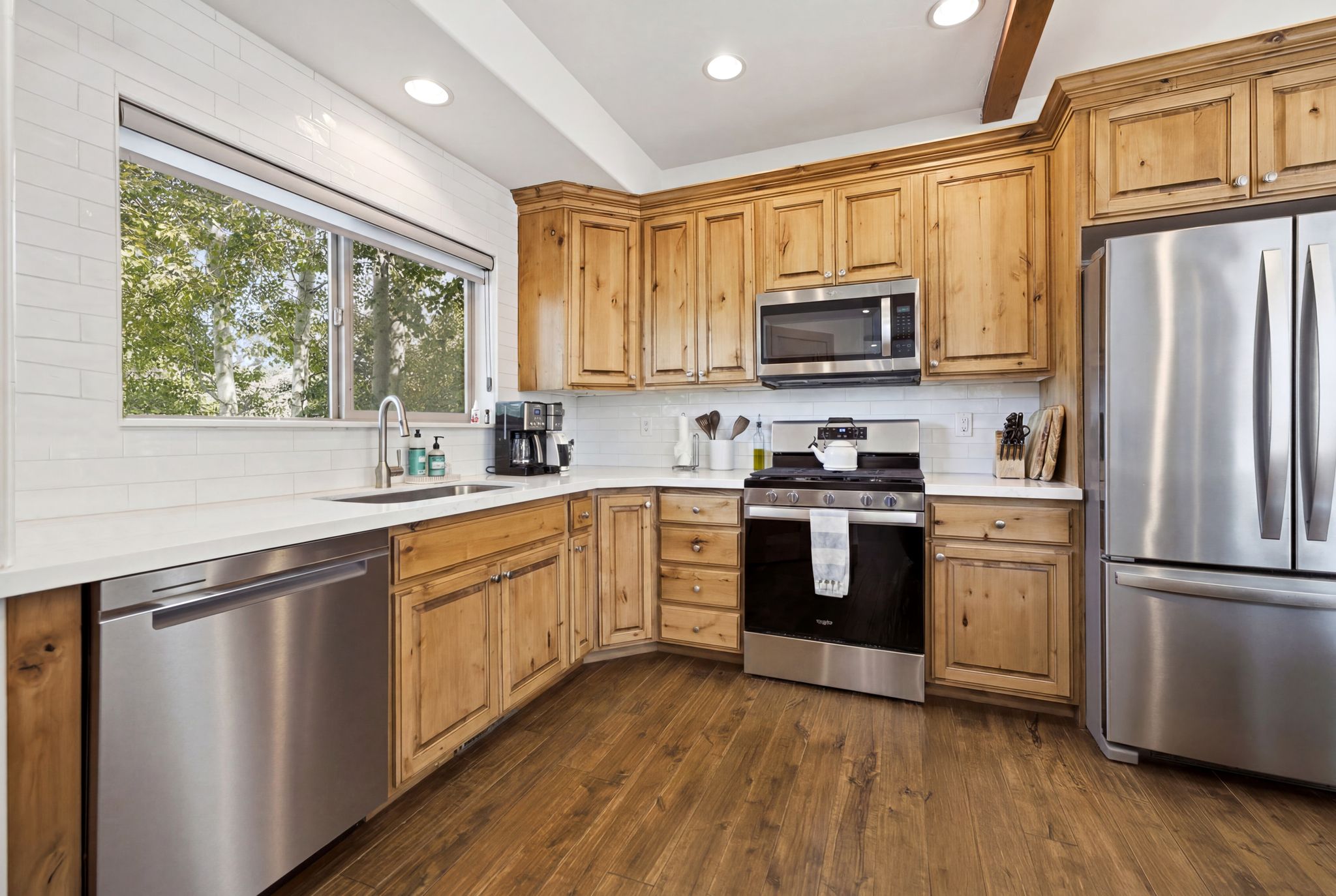 Kitchen featuring wood-finish cabinetry, stainless steel appliances, white subway tile backsplash, and composite countertops