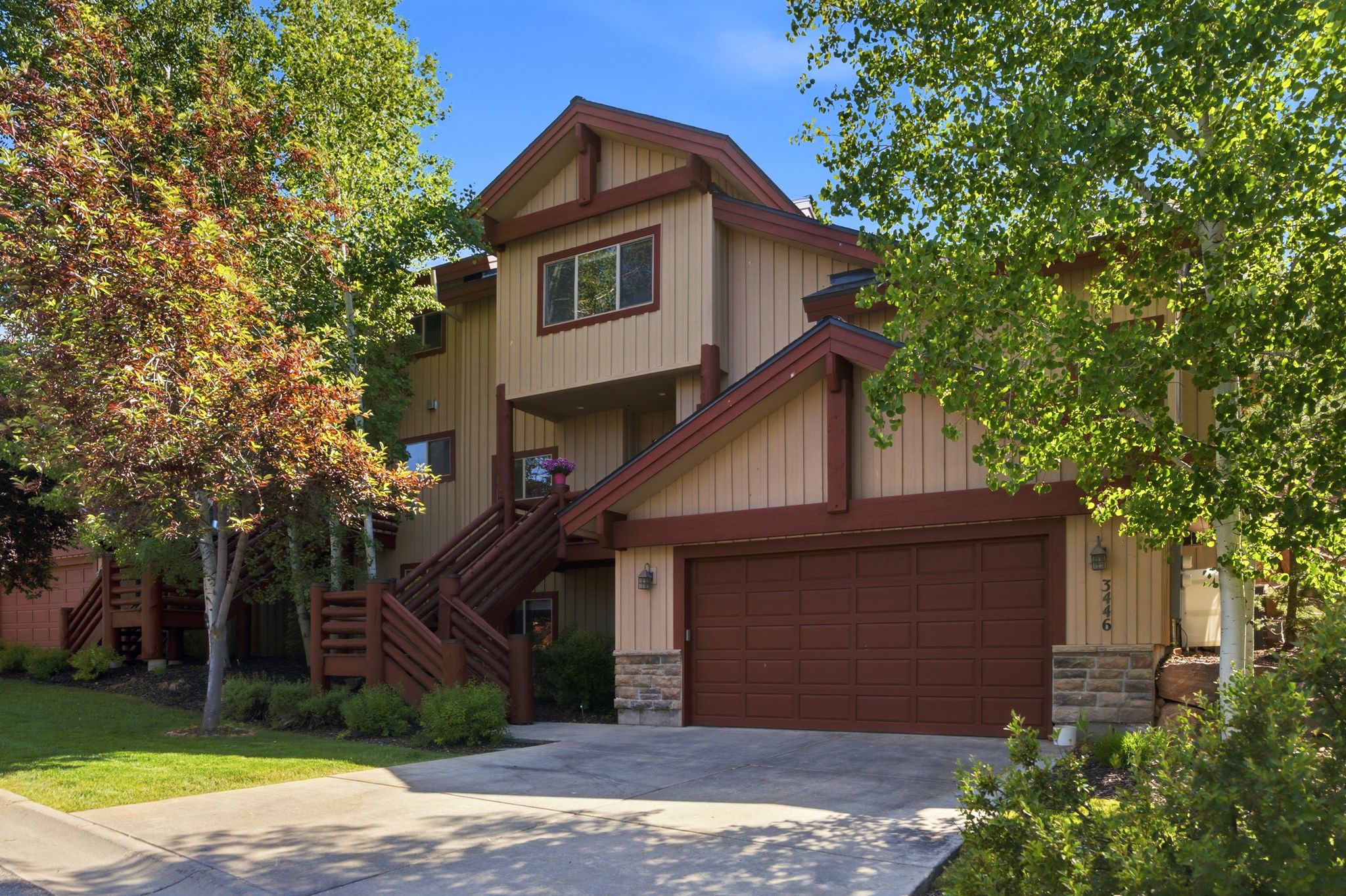 Multi-level exterior with a two-car garage, stone accents, and wood-toned siding