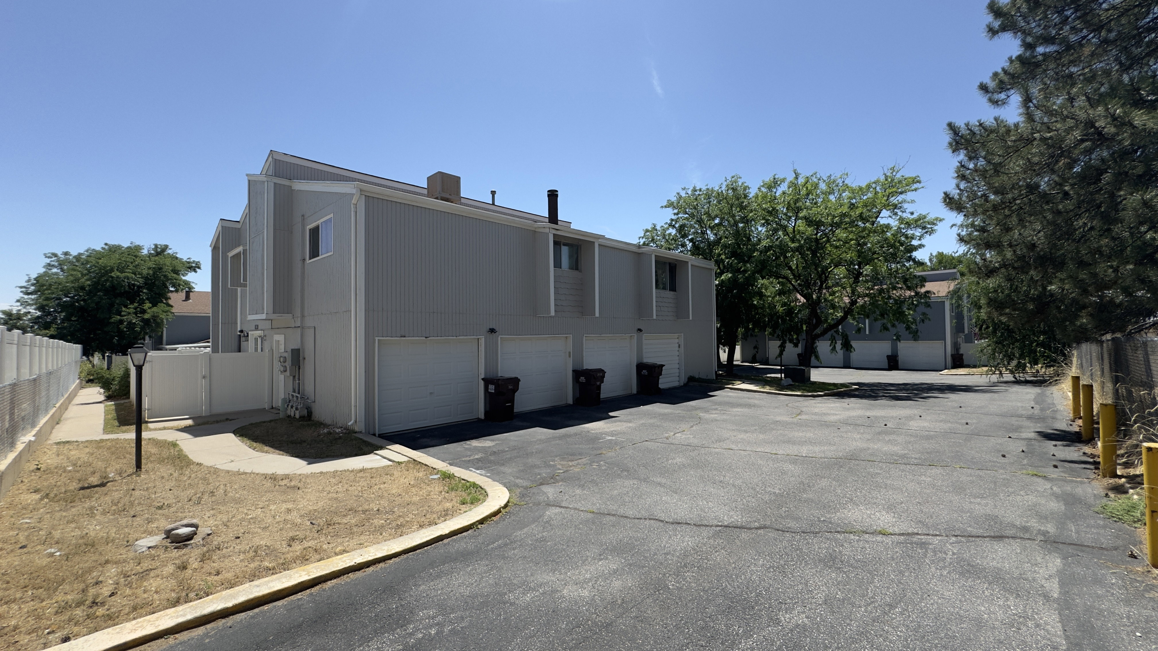 Two-story multi-unit structure featuring vertical panel siding and individual garage access.
