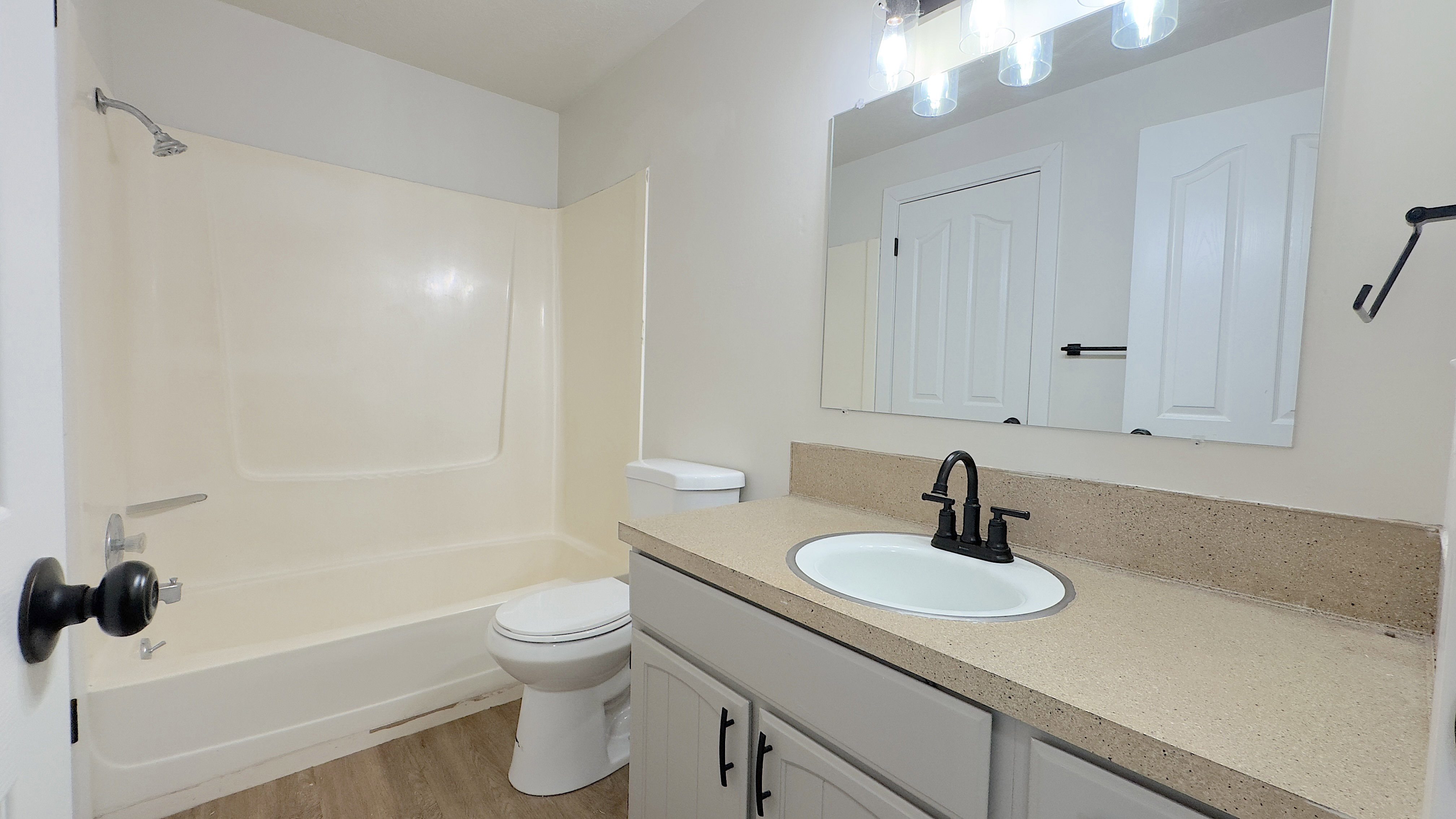 Bathroom featuring a single vanity with a solid surface countertop, an undermount sink, and a black-finish faucet