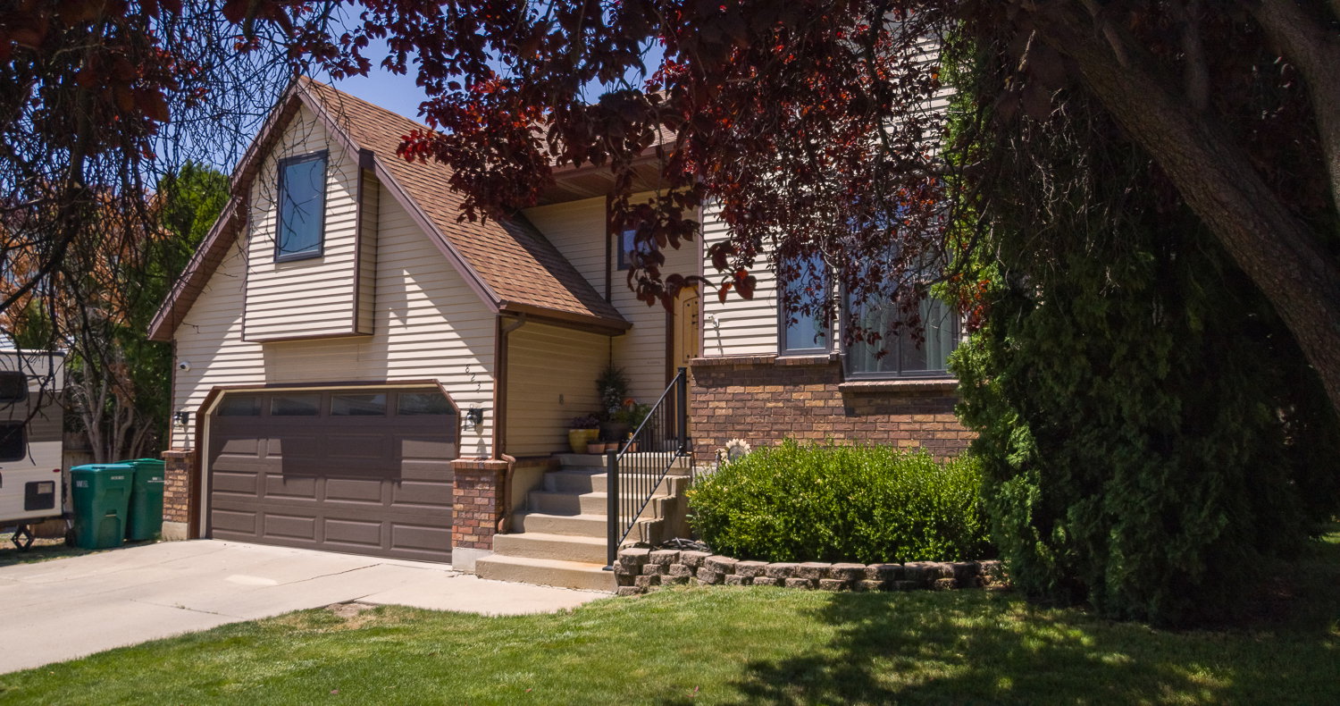 Front exterior featuring horizontal siding, a brown garage door, and a brick facade accent