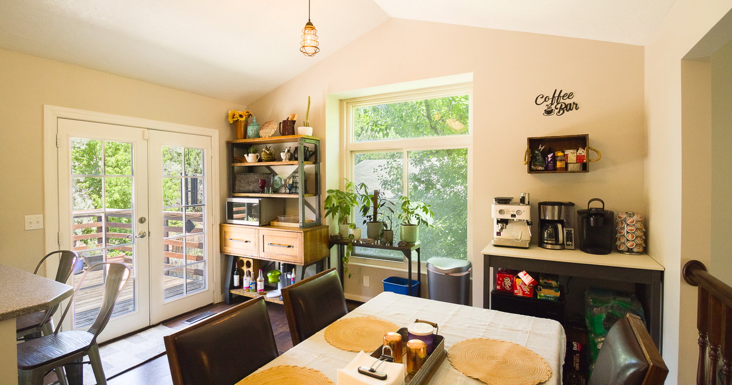 Vaulted ceiling dining area featuring French doors opening to an exterior deck, a large window, wood-finish flooring, and a built-in shelving unit with drawers