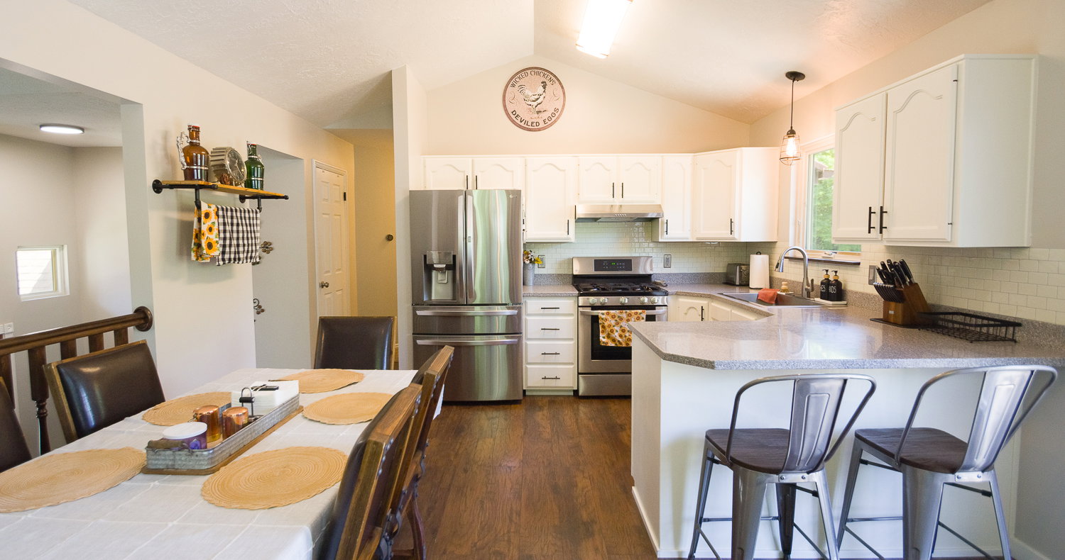 Kitchen featuring white cabinetry, stainless steel appliances, speckled countertops, and subway tile backsplash