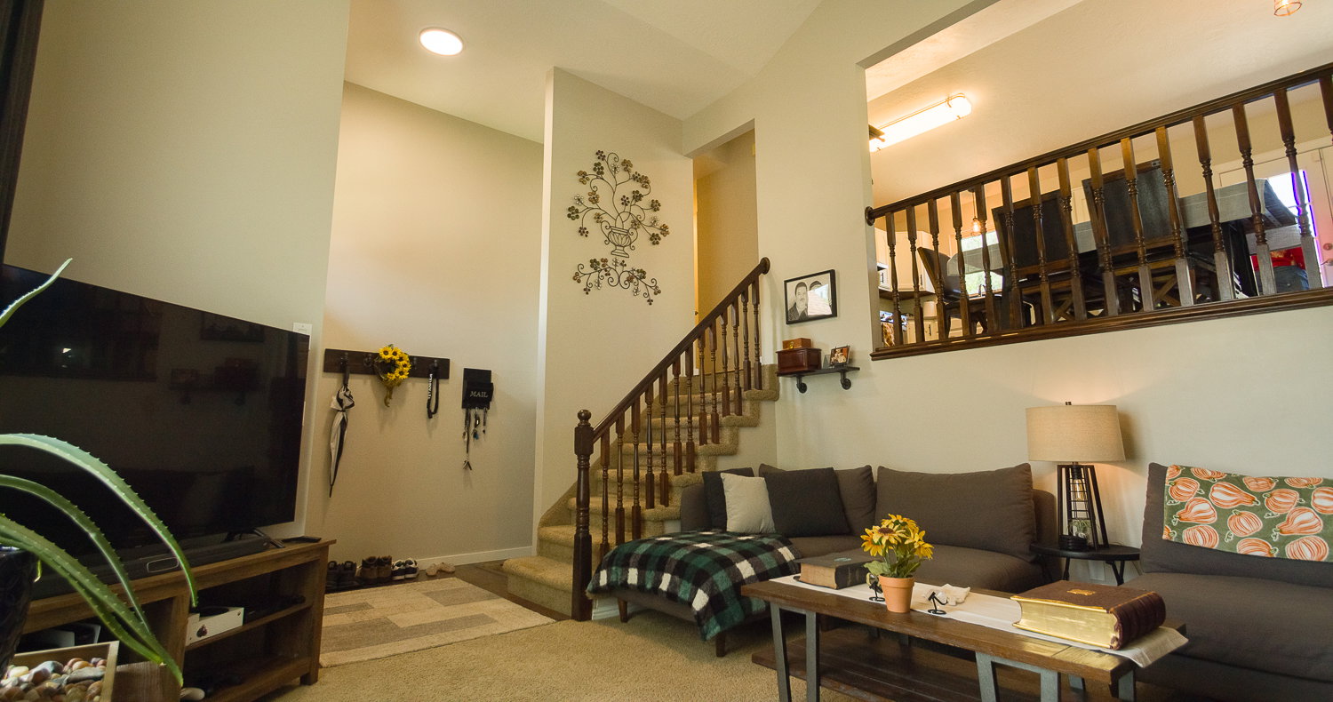 Living area featuring a partial vaulted ceiling, recessed lighting, carpeted stairs with wood balusters, and an upper-level half-wall with wood balusters