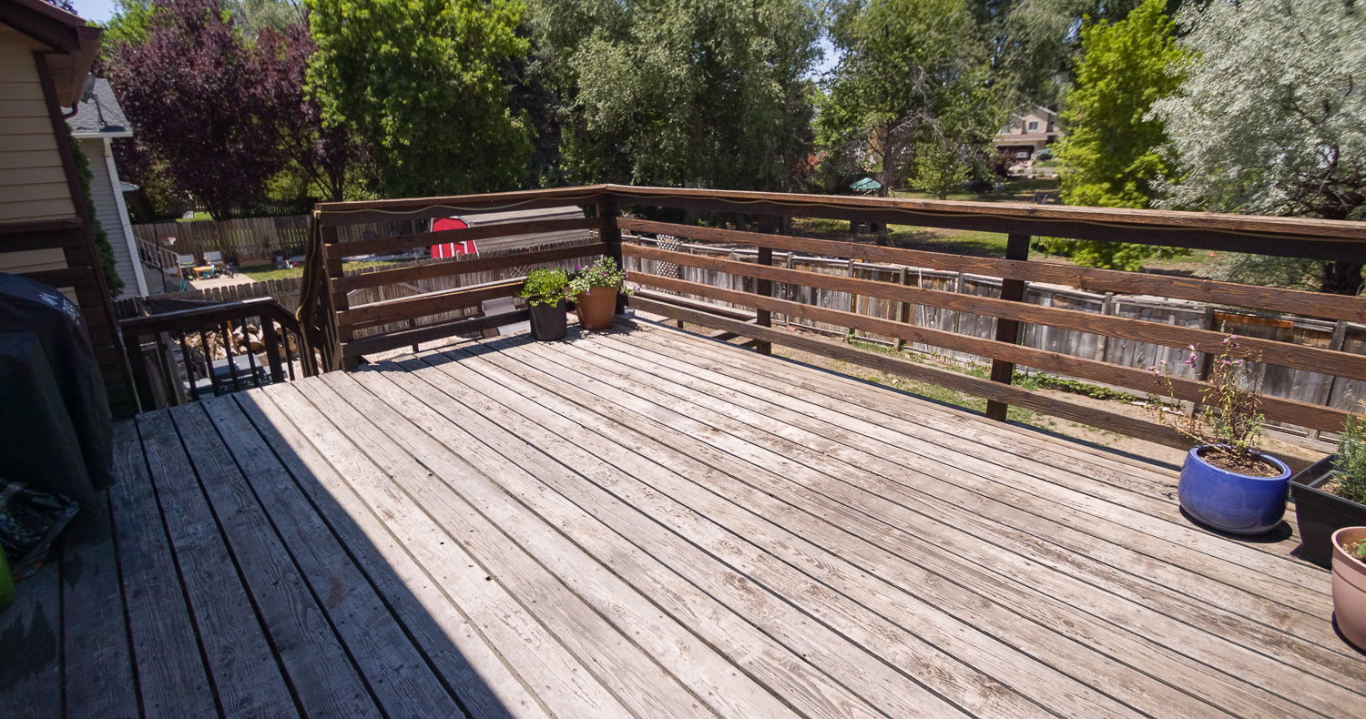 Spacious wood deck featuring a perimeter railing, built-in steps, and a privacy fence bordering the yard