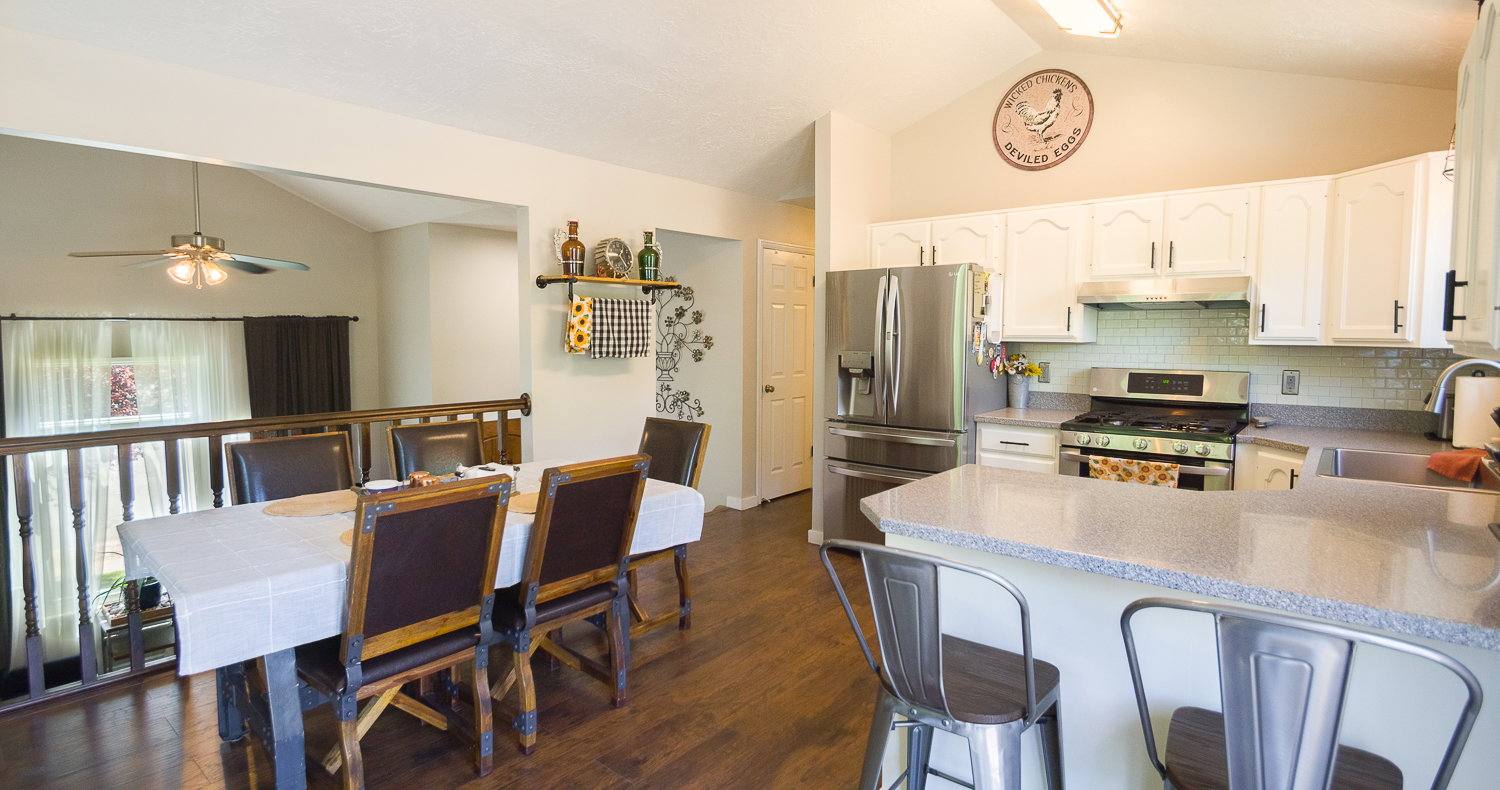 Kitchen featuring white cabinetry, stainless steel appliances, a tile backsplash, and a breakfast bar with seating