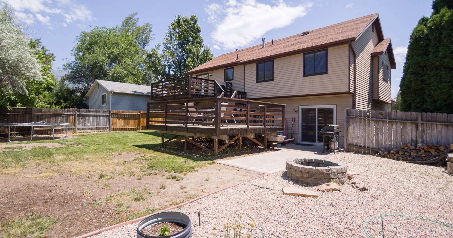 Expansive backyard featuring a multi-level wood deck, a patio with pavers, and a stone fire pit
