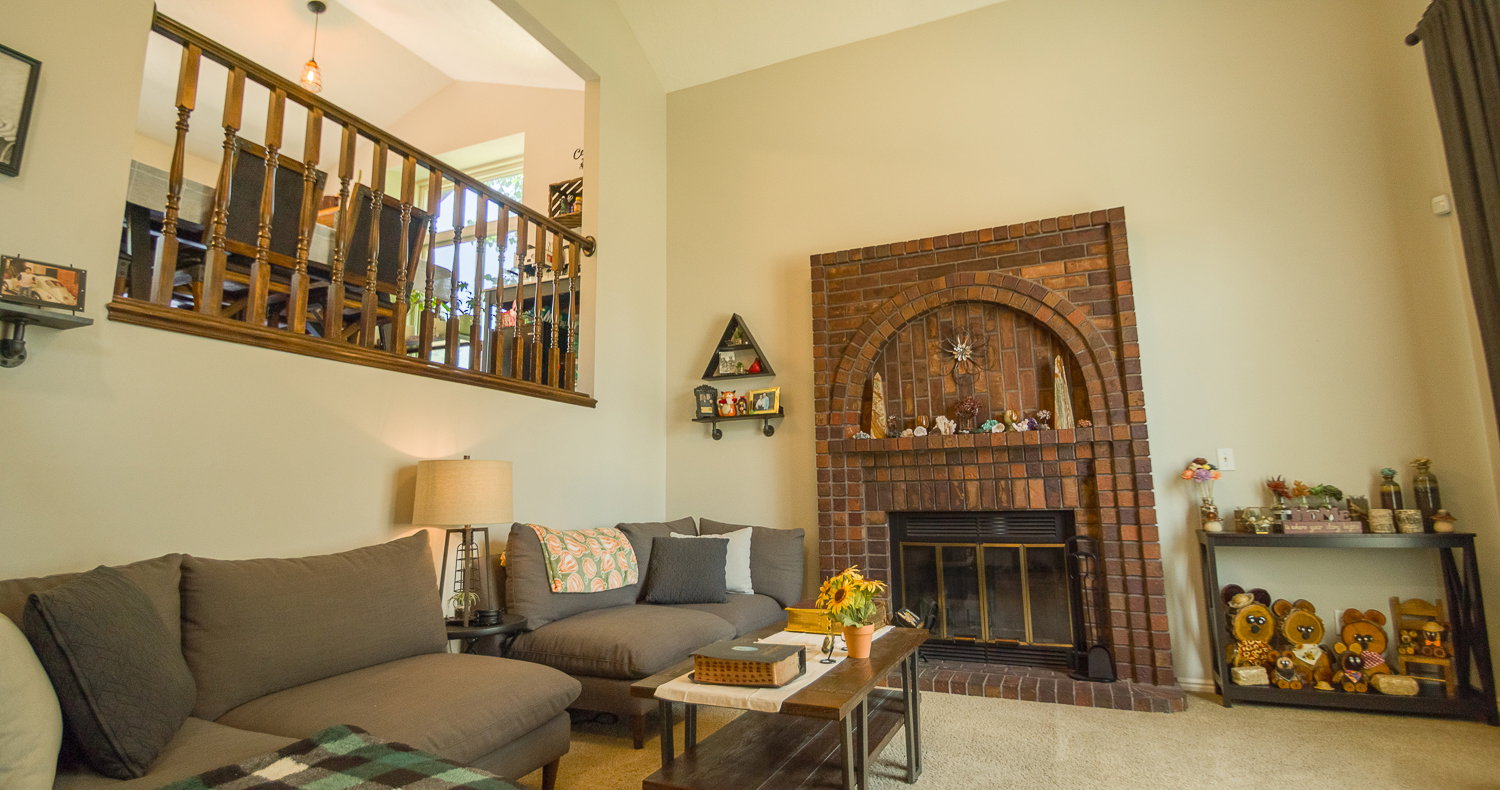 Living area featuring a floor-to-ceiling brick fireplace with an arched design, a brass firebox, and a hearth