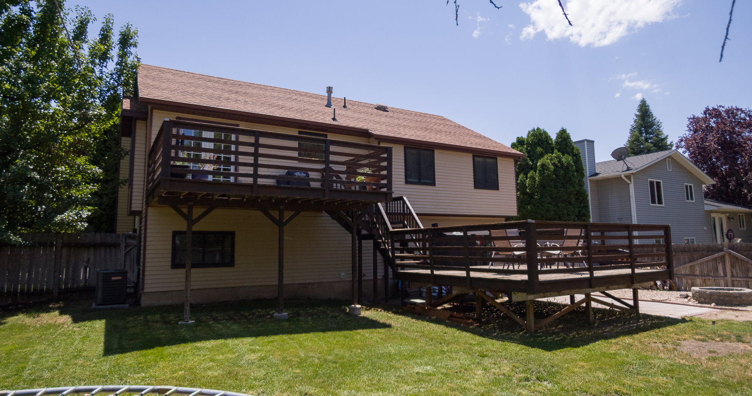 Two-story home with light-colored siding and a brown roof