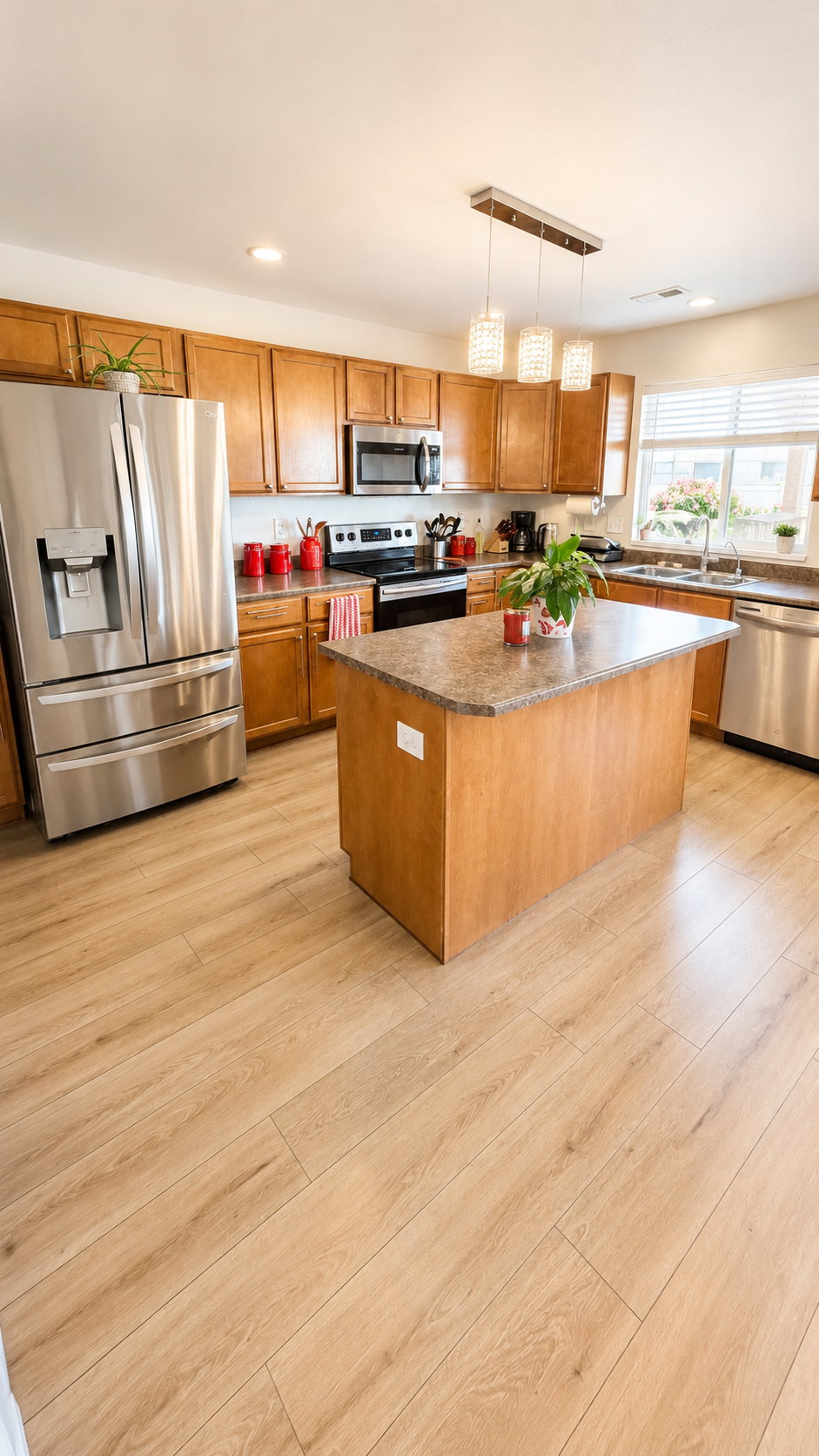 Kitchen featuring warm wood cabinetry, stainless steel appliances, a central island with a countertop, wood-finish flooring, and pendant lighting