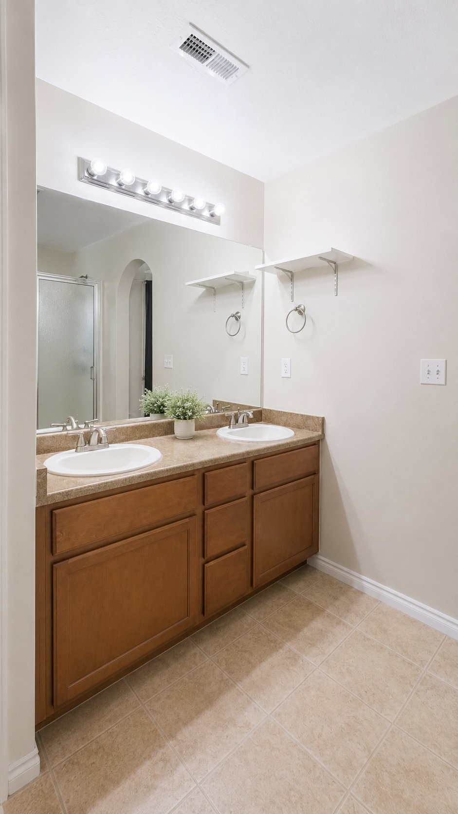 Double vanity with oval sinks, wood-finish cabinetry, and a light-toned countertop
