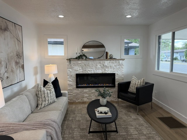 Living area featuring a textured stone-clad fireplace with an electric insert, recessed lighting, and wood-finish flooring