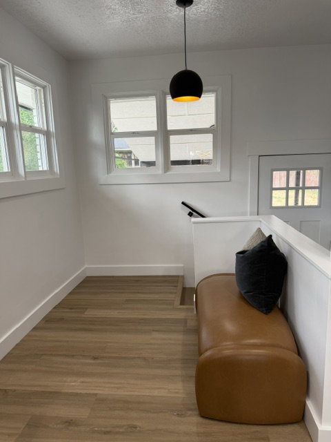 Upper landing featuring wood-finish flooring, white trim, and multiple windows