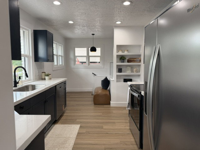 Modern kitchen featuring dark cabinetry, light countertops, wood-finish flooring, recessed lighting, and stainless steel appliances