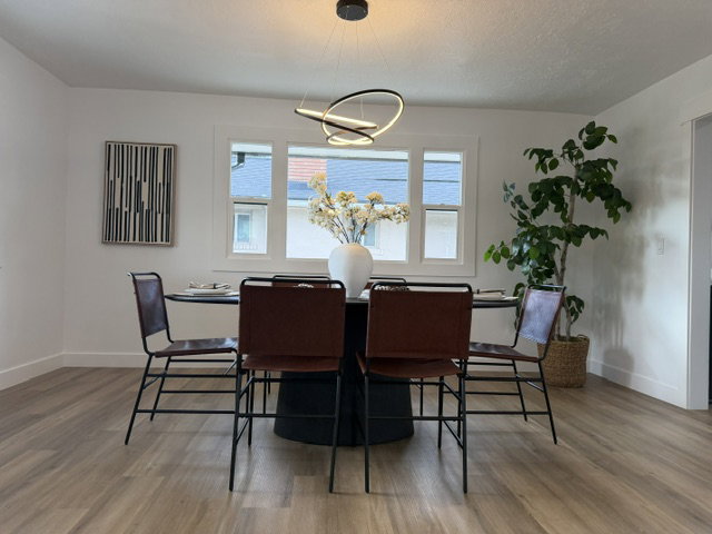 Dining area featuring wood-finish flooring, white walls, and a modern chandelier