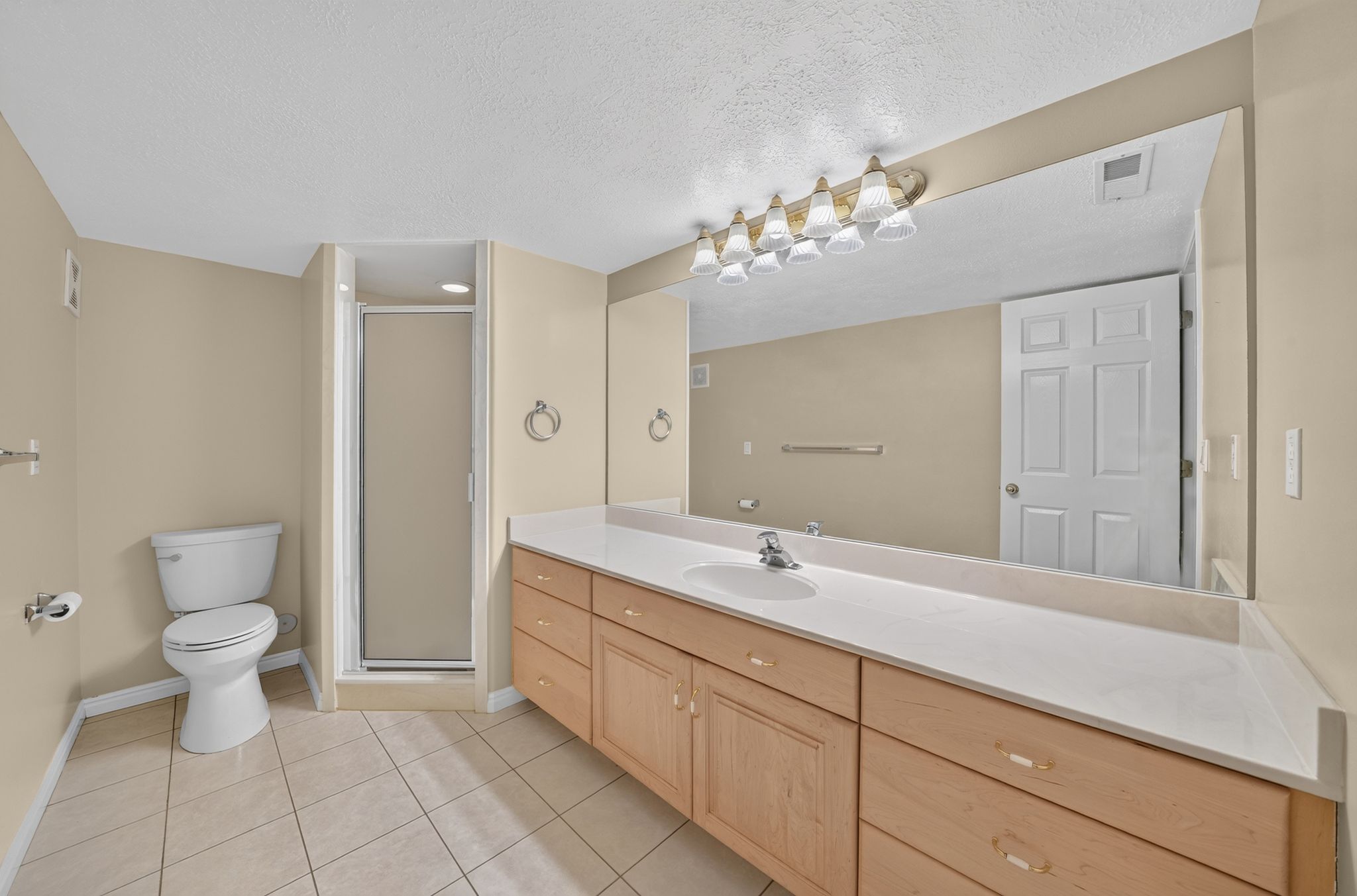 Bathroom featuring a long vanity with light wood cabinetry and a white countertop