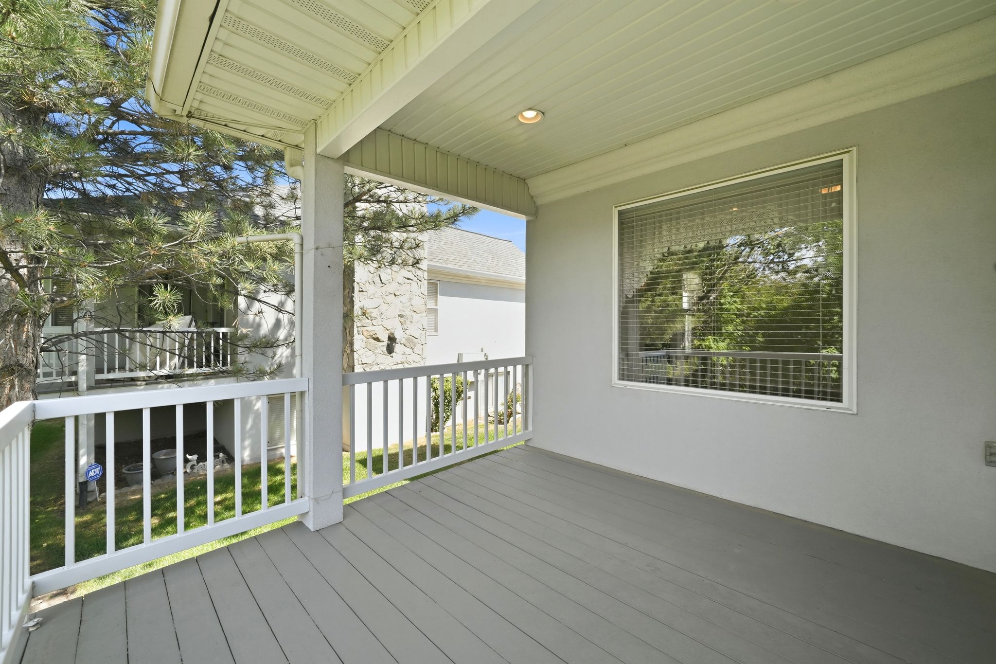 Covered porch with wood-finish decking and white railings