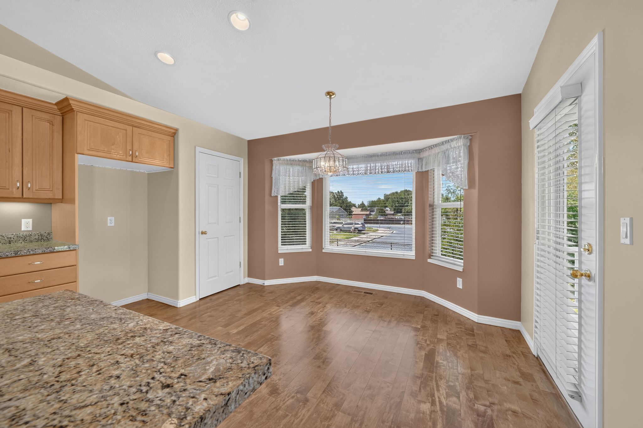 Dining area featuring a bay window, wood-finish flooring, and a decorative chandelier