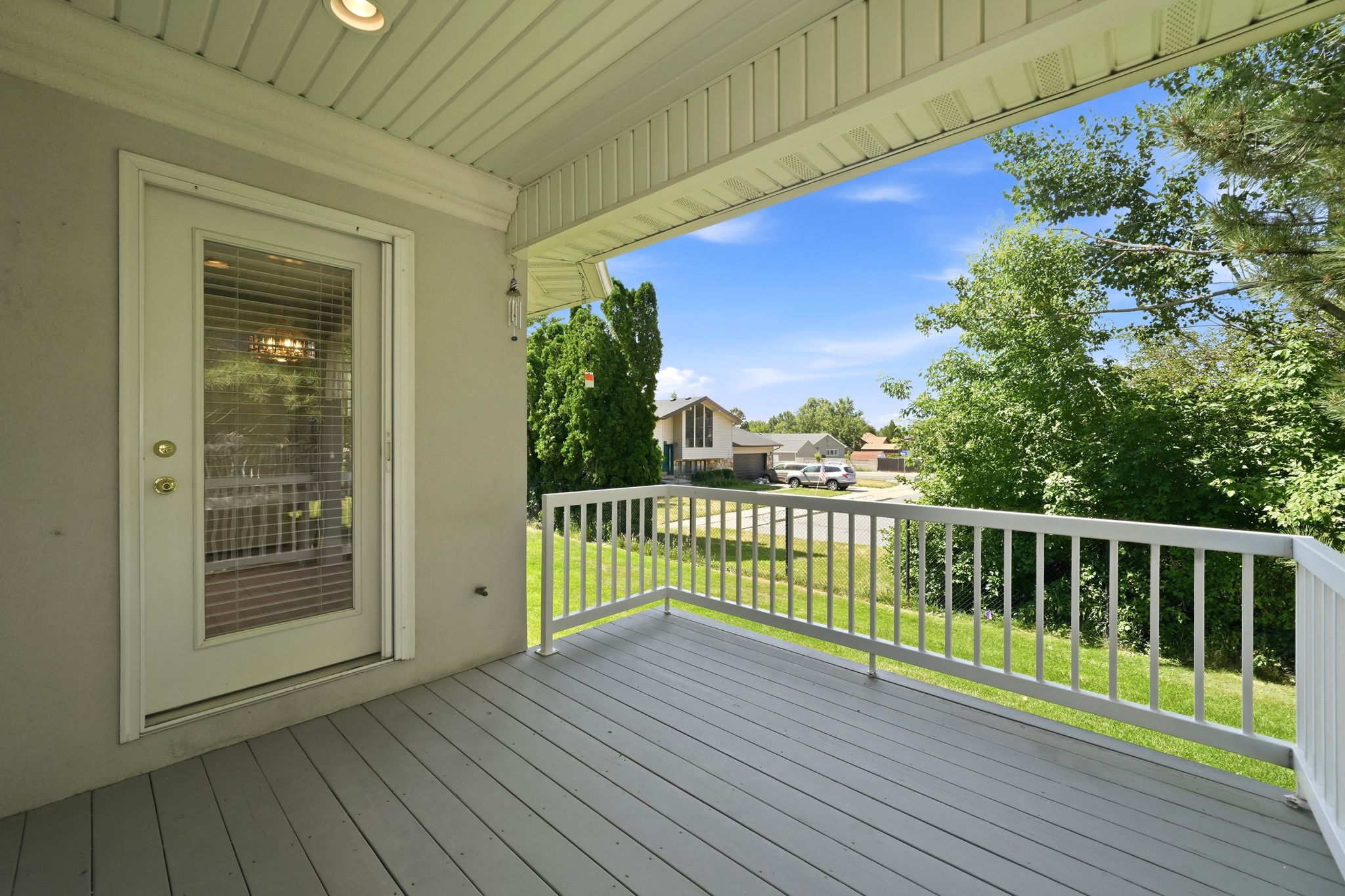 Covered porch with wood-finish decking and white railings