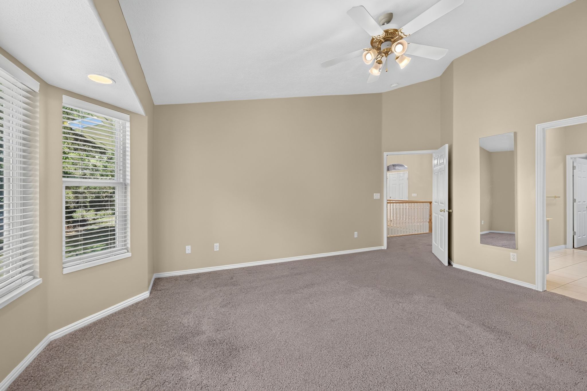 Spacious room featuring vaulted ceilings, a ceiling fan with integrated lighting, recessed lighting, and bay windows