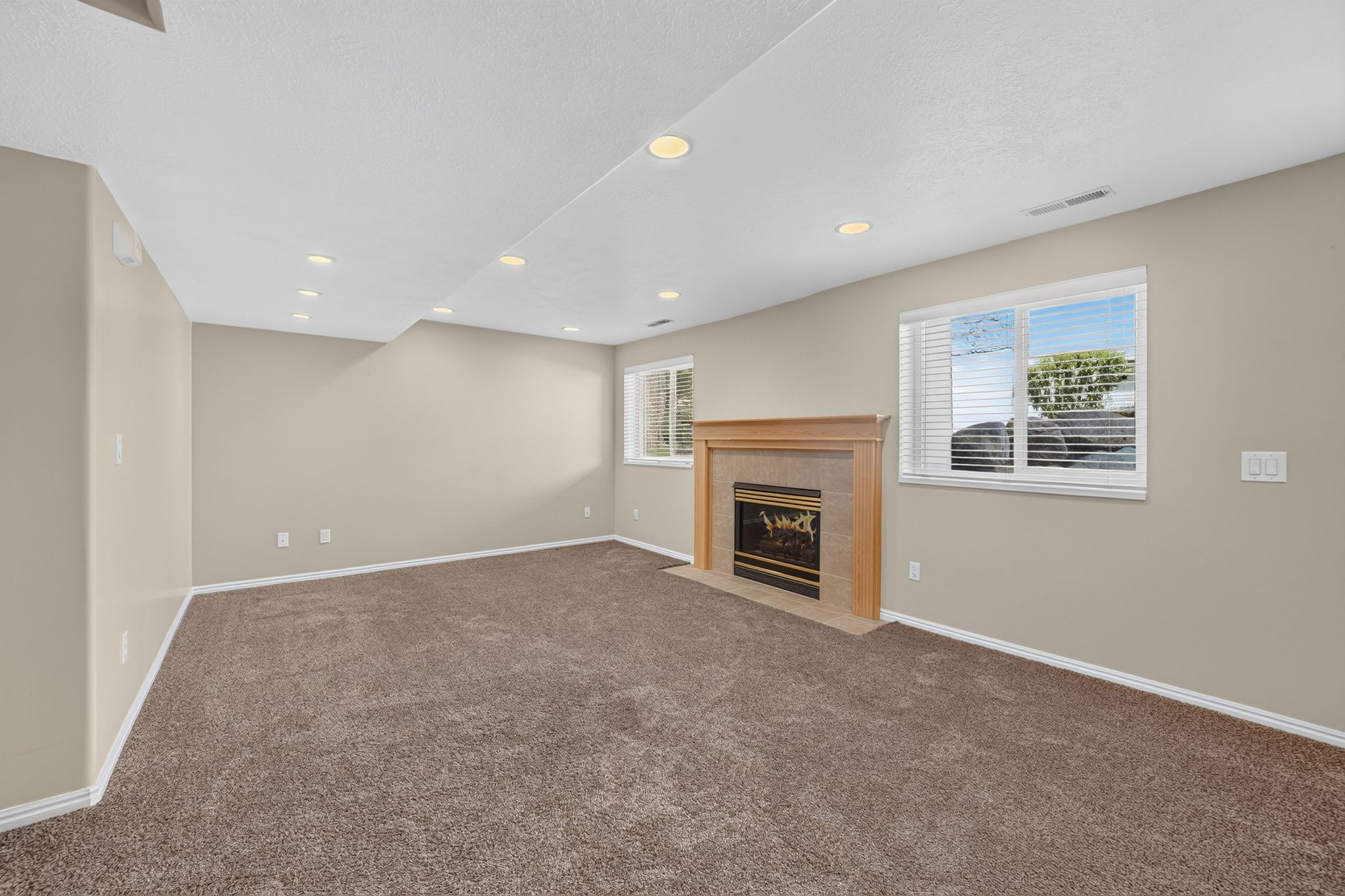 Spacious room featuring a central fireplace with a wood-finish mantel and tile surround