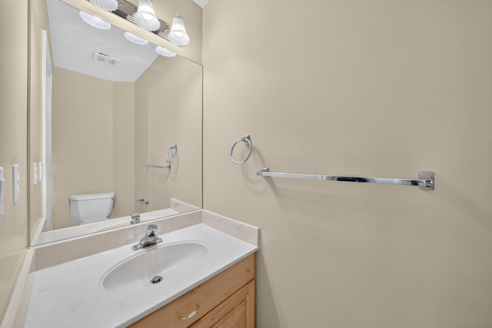 Vanity with an integrated sink, polished chrome faucet, and coordinating vanity light fixture