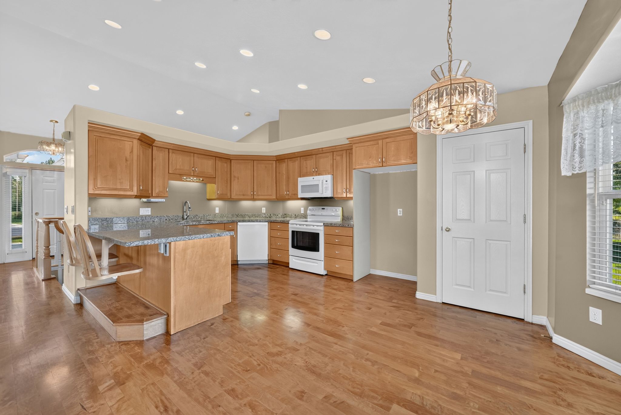 Kitchen featuring wood-finish flooring, recessed lighting, wood cabinetry, stone countertops, and a built-in breakfast bar