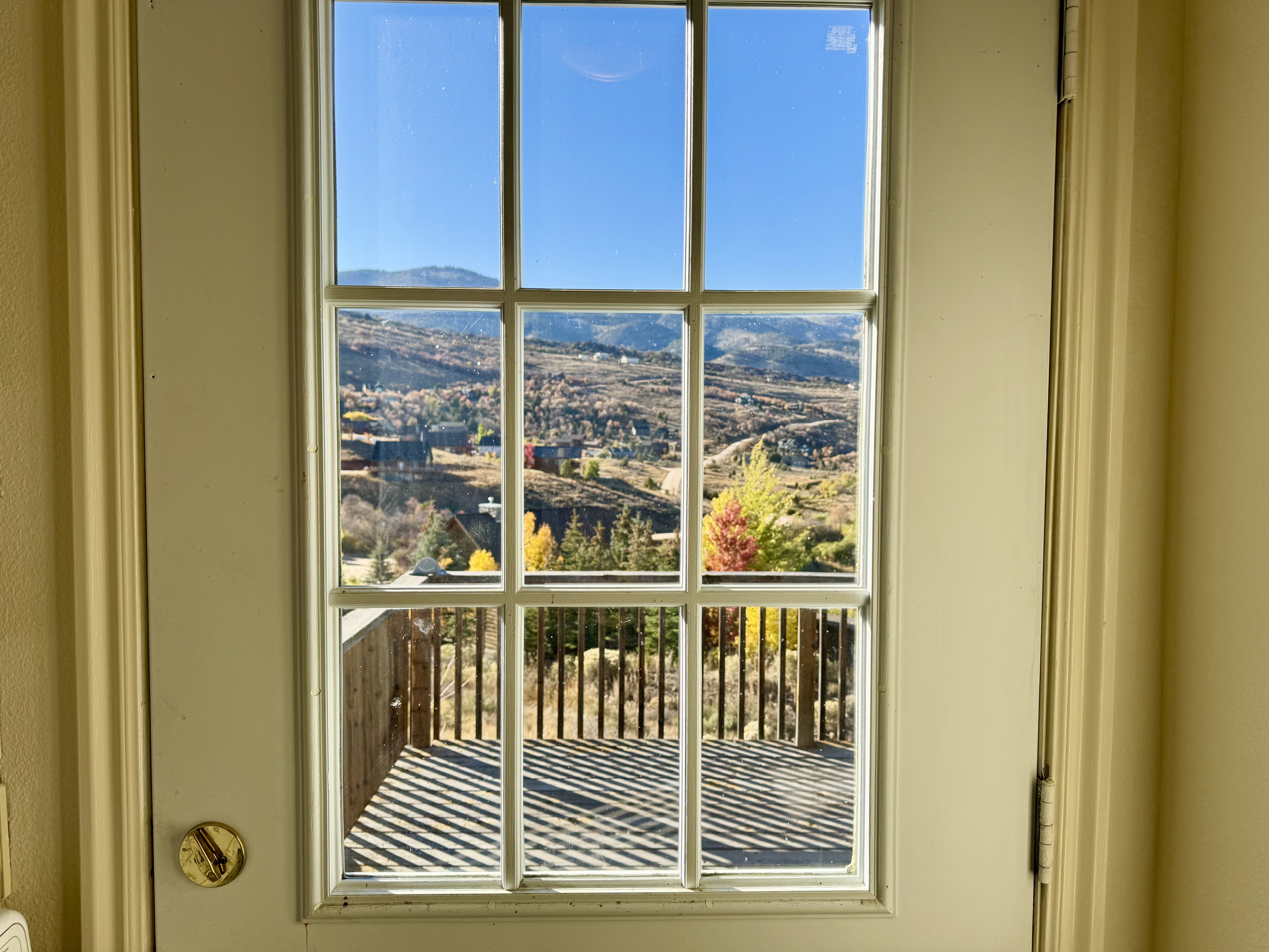 Door with multipane window overlooking a wooden deck and mountainous landscape