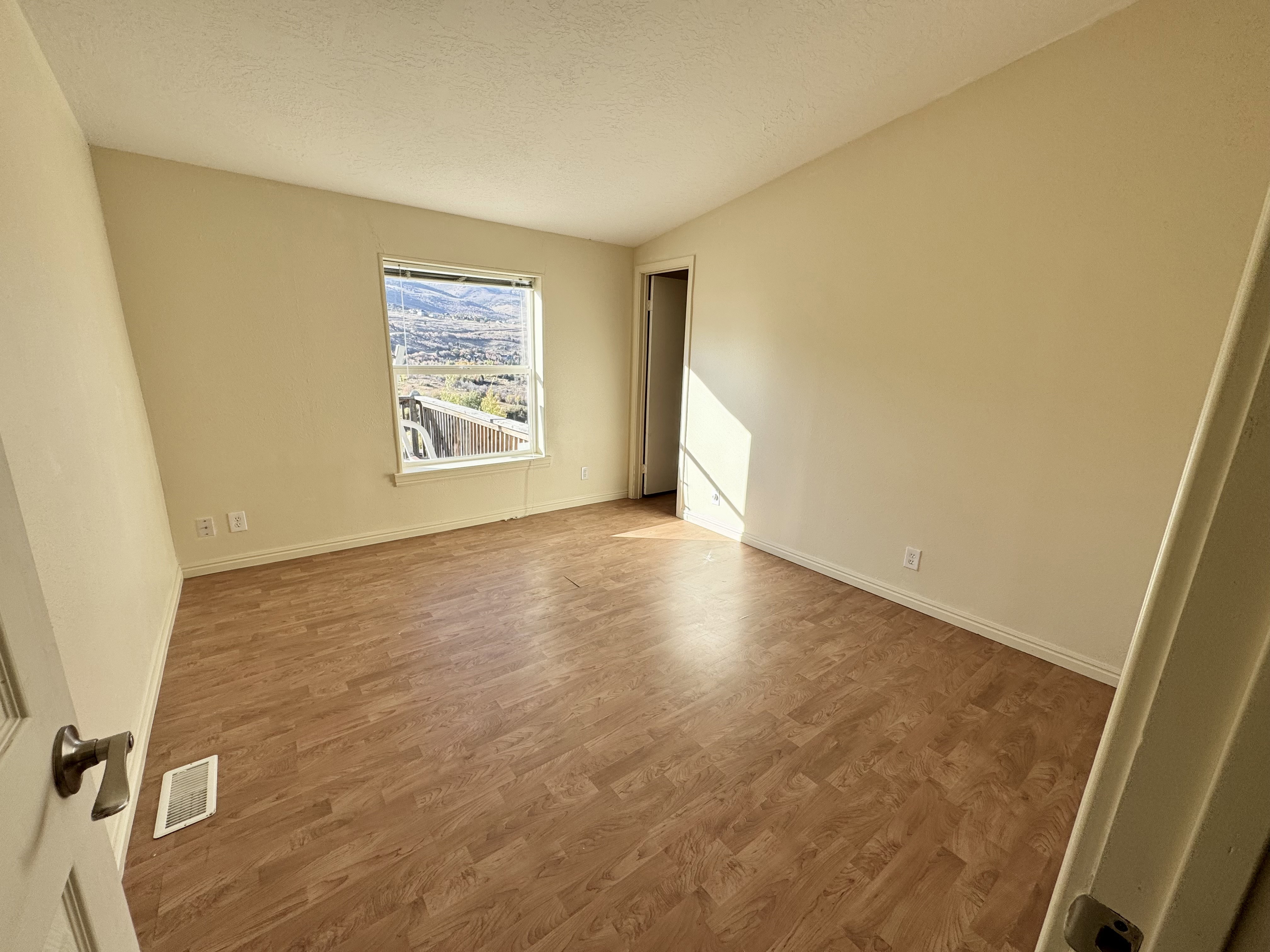 Room featuring wood-finish flooring, neutral wall tones, and a window with a mountain and city backdrop