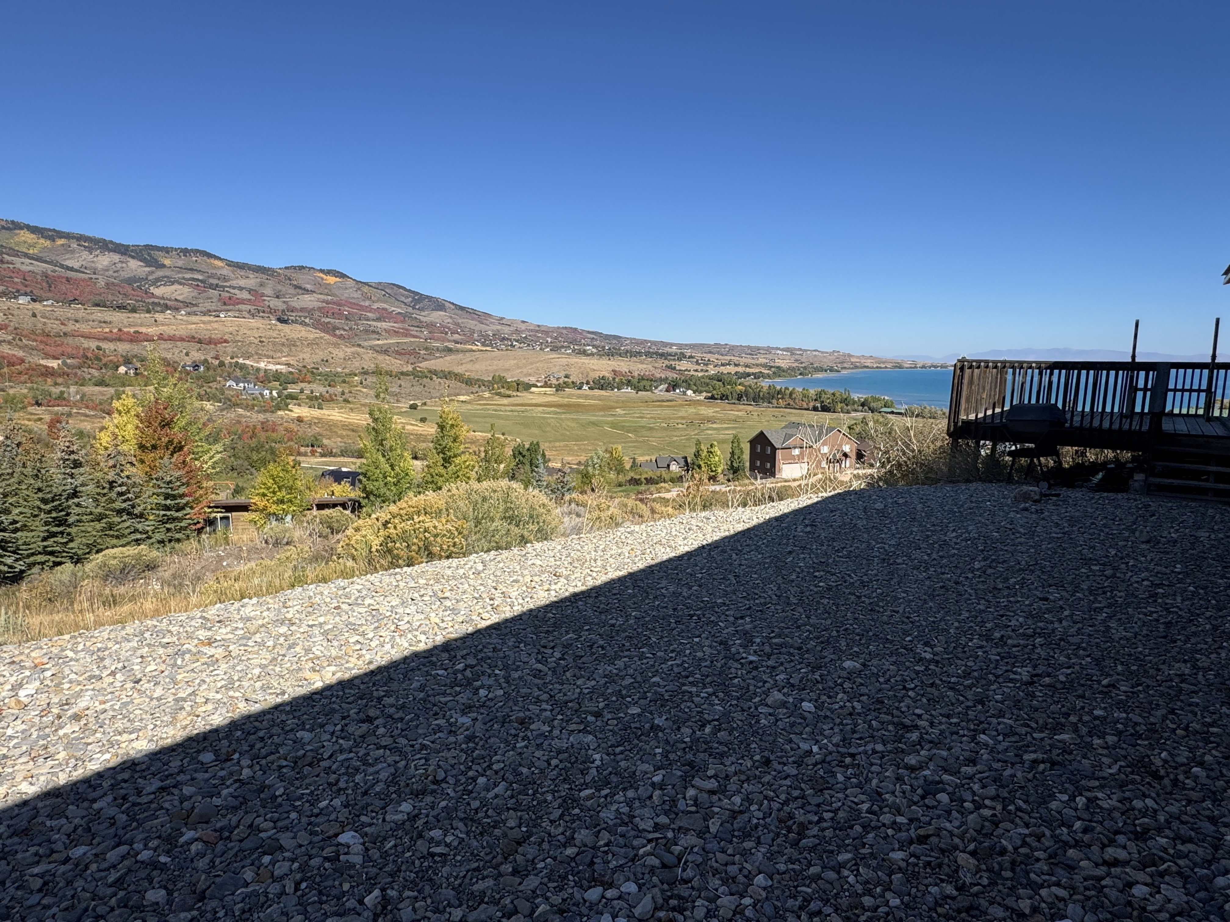 Gravel hardscaping with a wooden deck offering water and mountain scenery