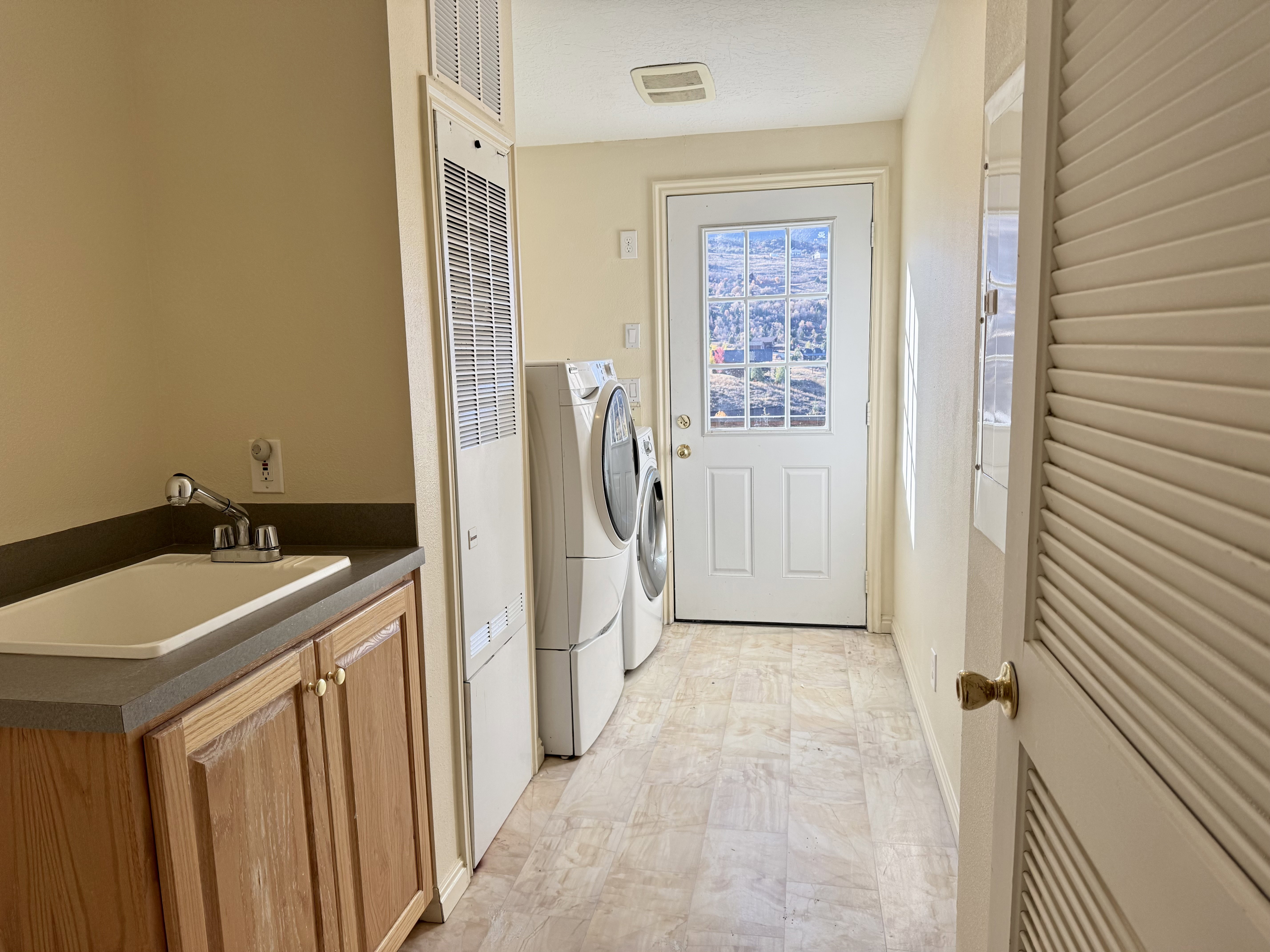 Utility area featuring a built-in sink with a countertop, wood cabinetry, and neutral-toned flooring
