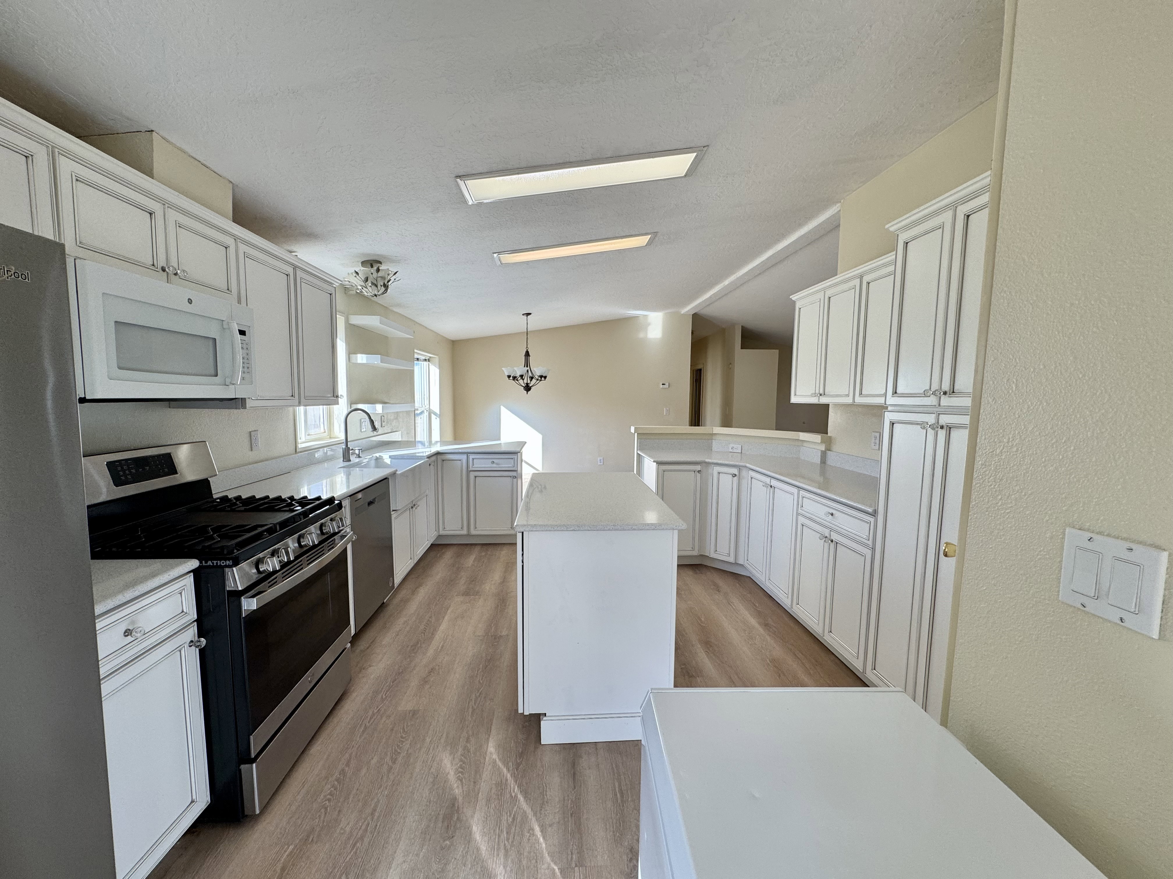 Expansive kitchen featuring white cabinetry, light-toned countertops, and wood-finish flooring