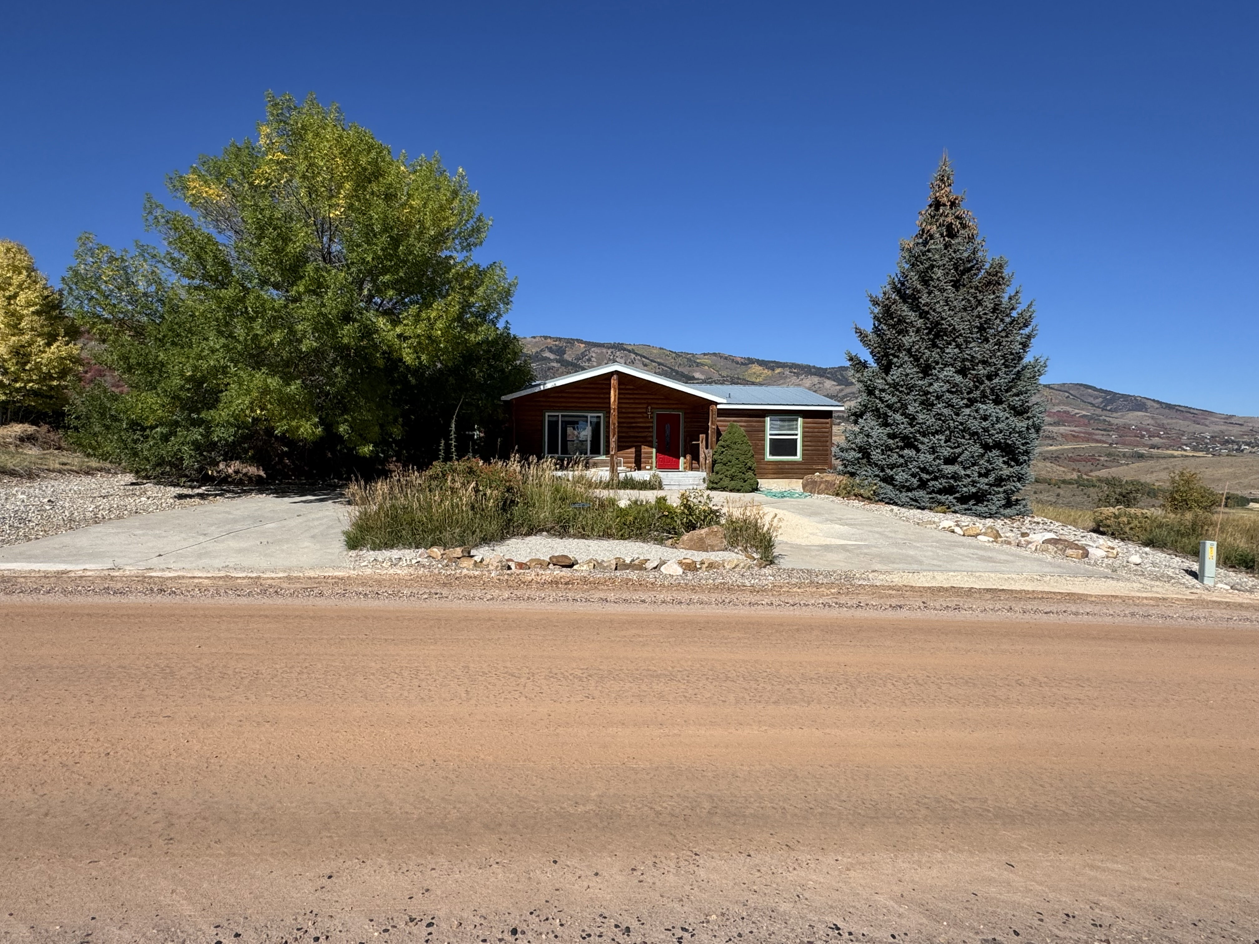 Ranch-style residence featuring wood-paneled siding and a contrasting red entry door