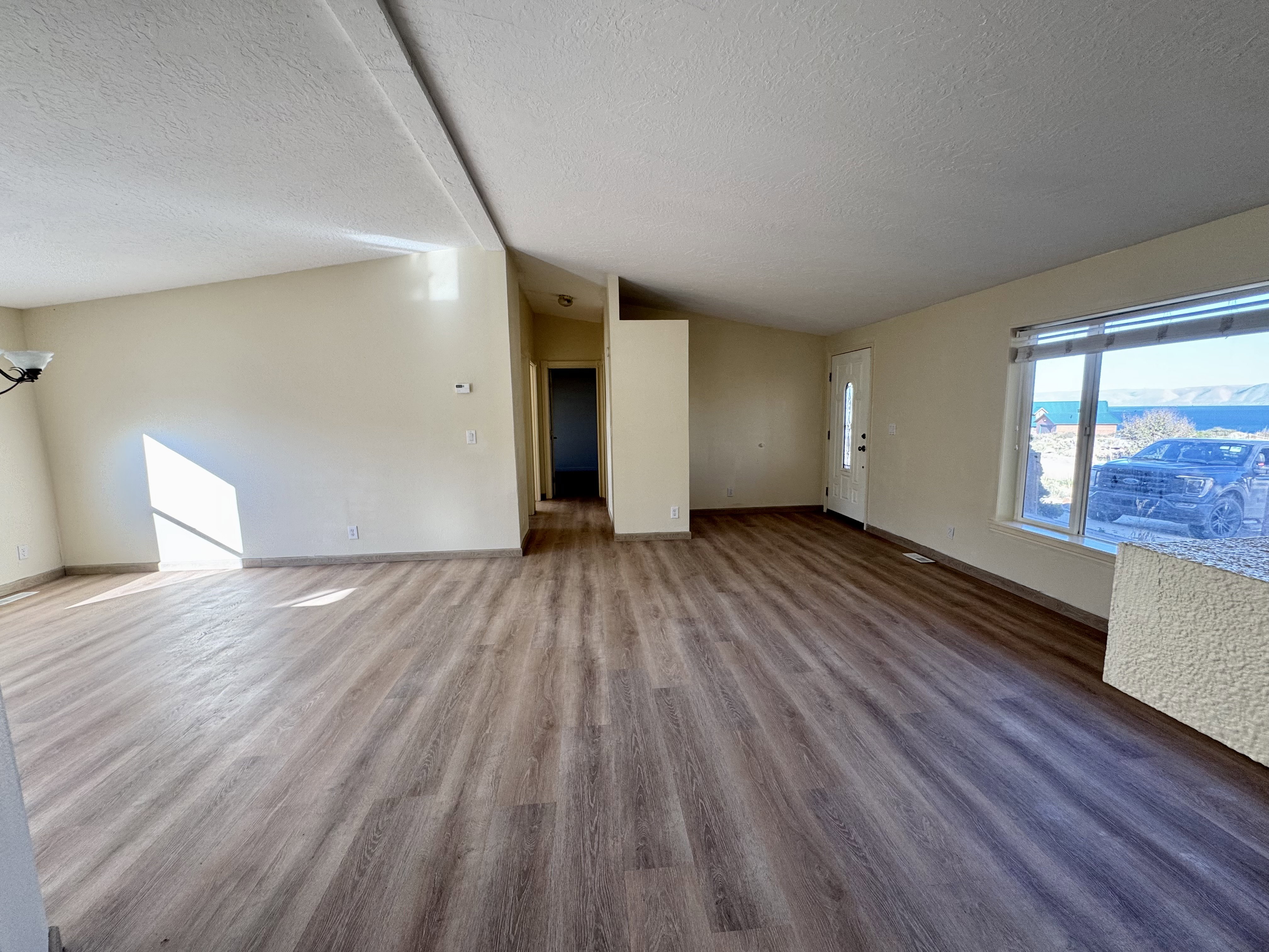 Spacious interior featuring wood-finish flooring, neutral-toned walls, and a vaulted ceiling
