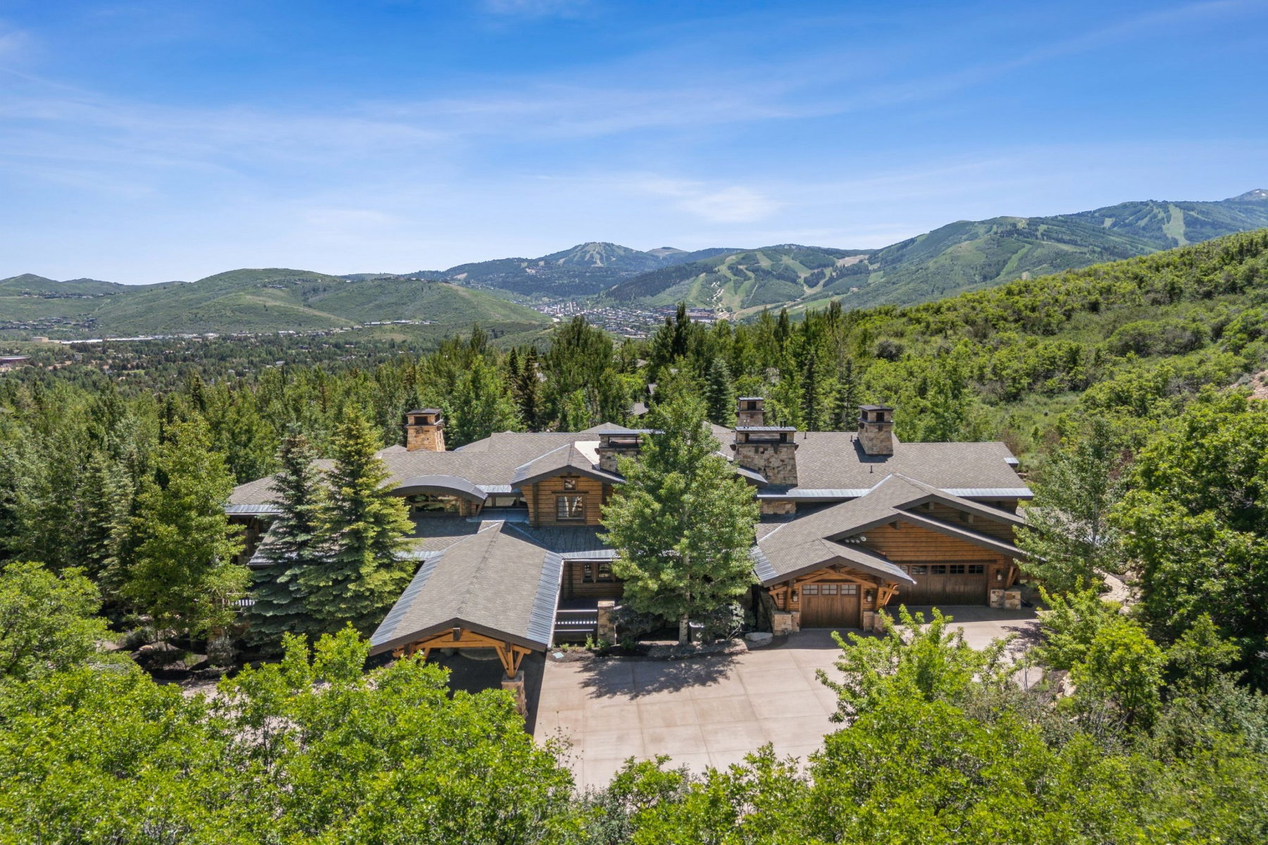 Expansive mountain property featuring a multi-level architectural design, wood siding, and multiple stone chimneys
