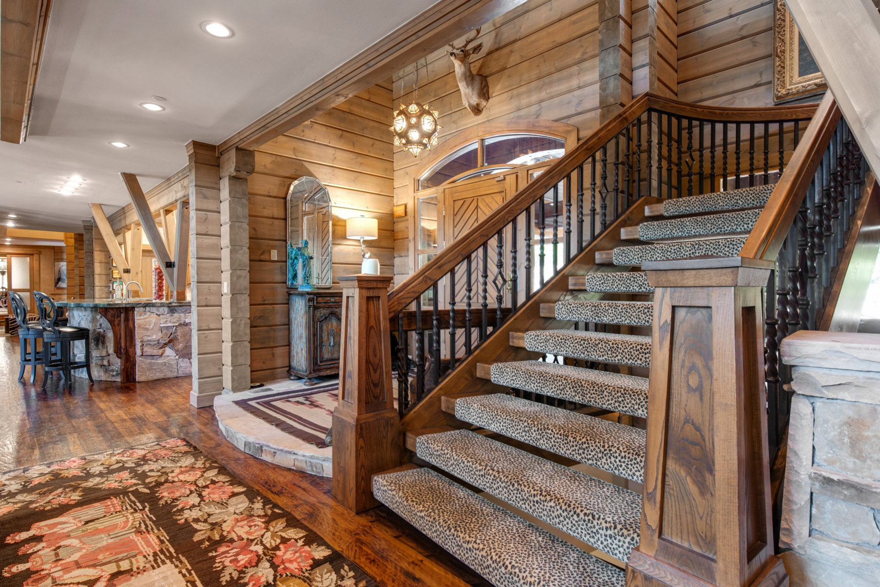 Grand staircase featuring wood treads, dark wood newel posts, and wrought iron balusters