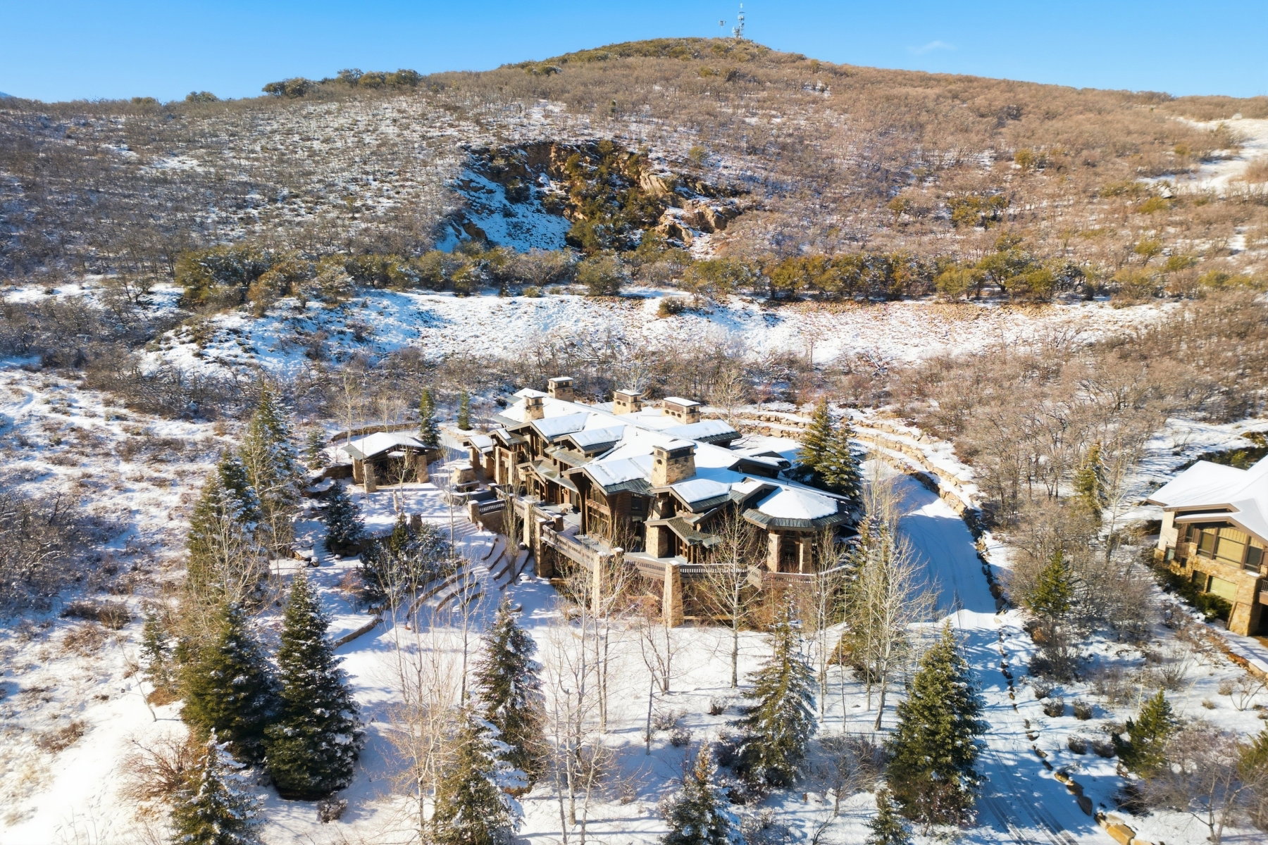Multi-level residence featuring a stone and wood exterior with multiple balconies and a snow-covered roof