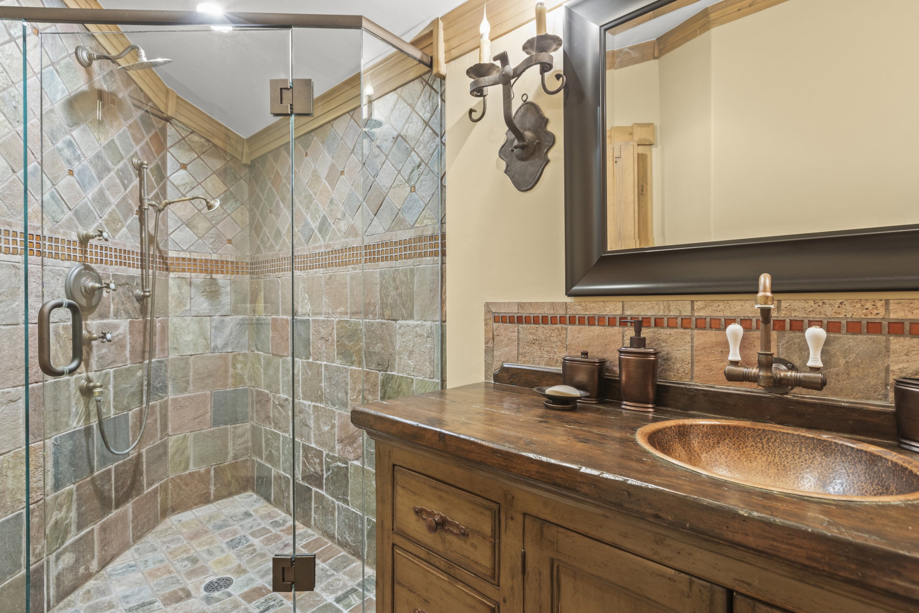 Shower with glass enclosure, multi-tone tile surround, and dual showerheads