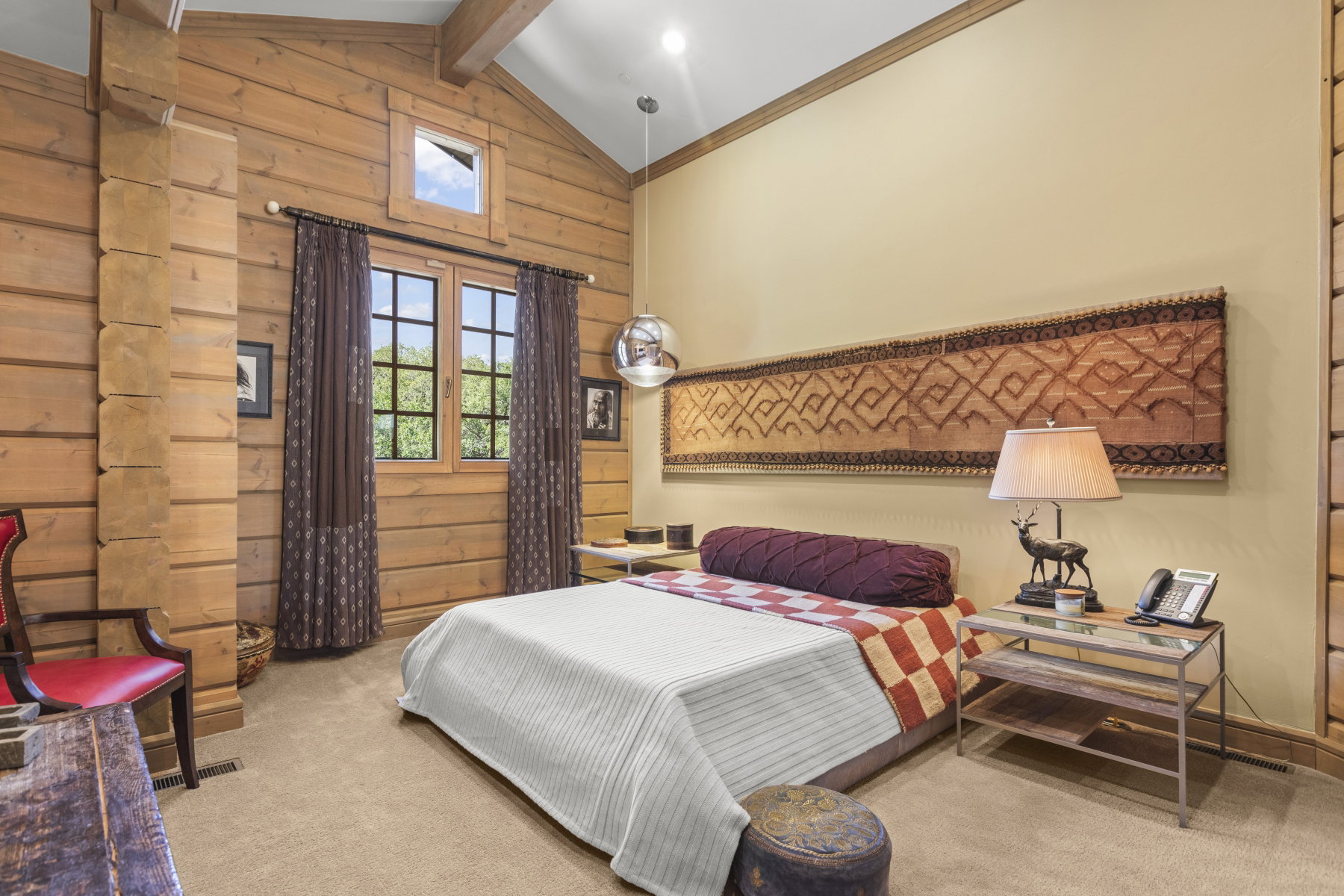 Vaulted ceiling with wood beams, light wood paneling, and a large window with grid panes