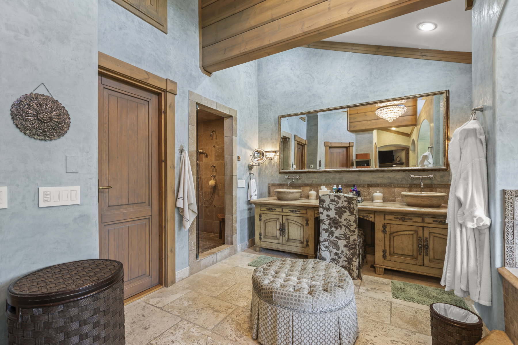 Spacious bathroom featuring a dual vanity with vessel sinks, a large mirror, a separate shower enclosure, and exposed wood ceiling beams