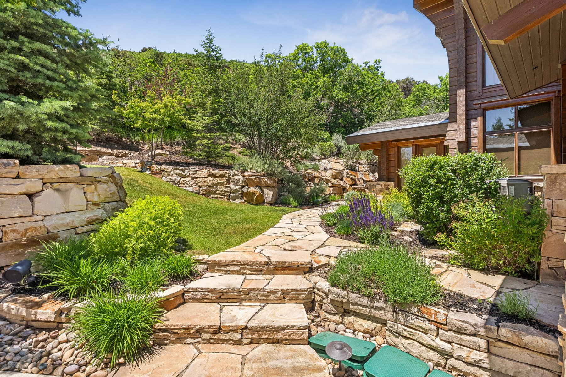 Terraced landscaping featuring natural stone retaining walls, flagstone pathways, and mature greenery